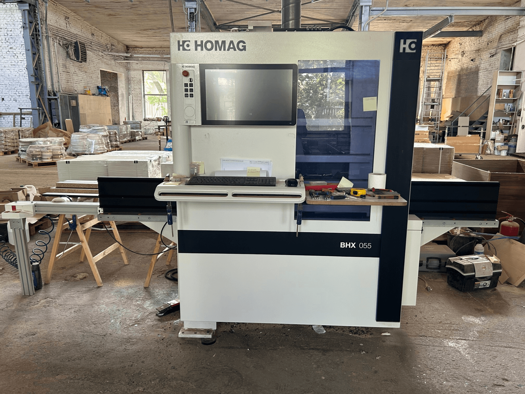 Centro di lavorazione CNC HOMAG WEEKE OPTIMAT BHX 055, vista frontale, con pannello di controllo e area di lavoro dotata di utensili.