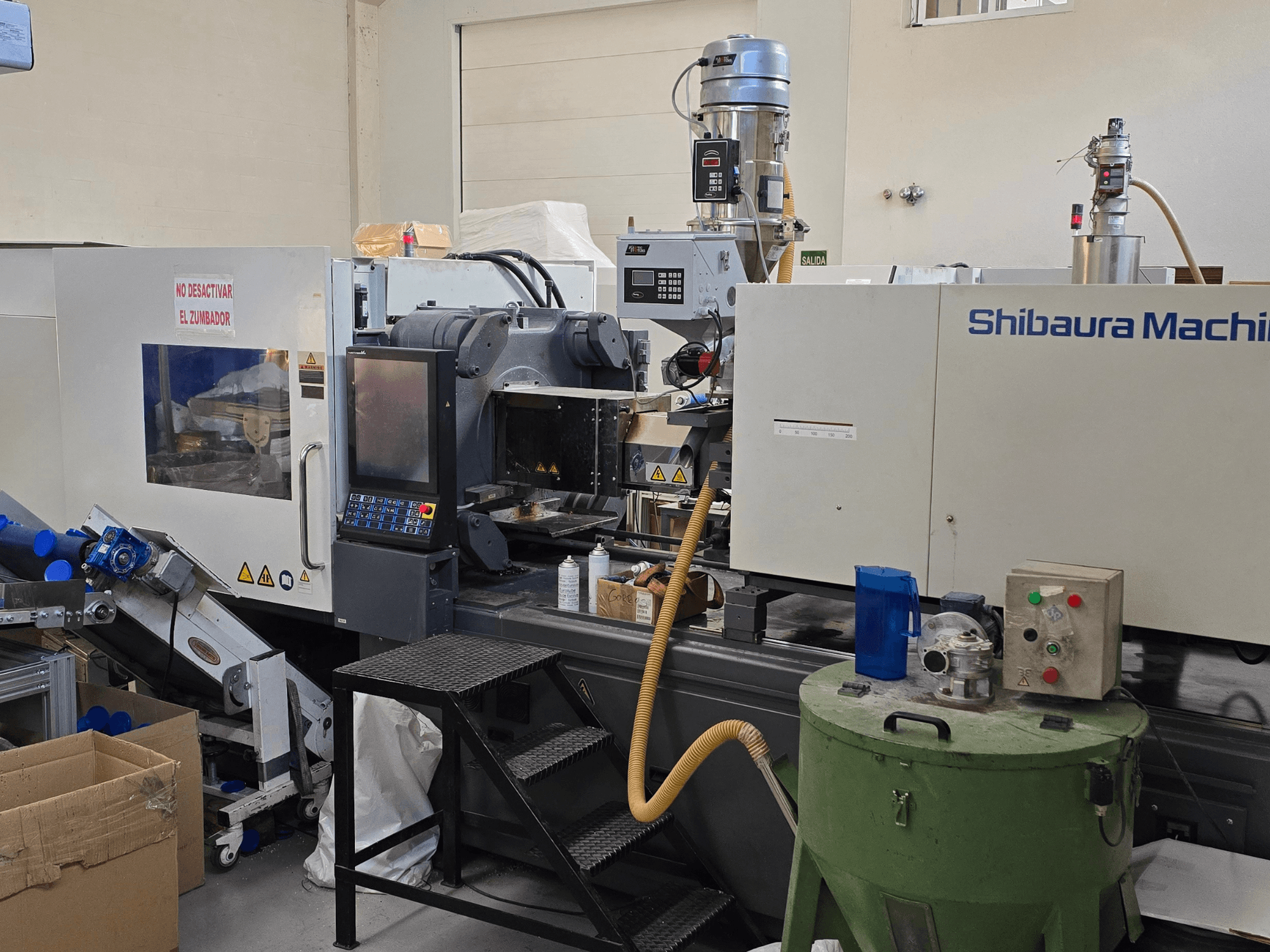 Vista frontale della pressa a iniezione elettrica SHIBAURA EC230SXIII-8A con pannello di controllo e attrezzature adiacenti.