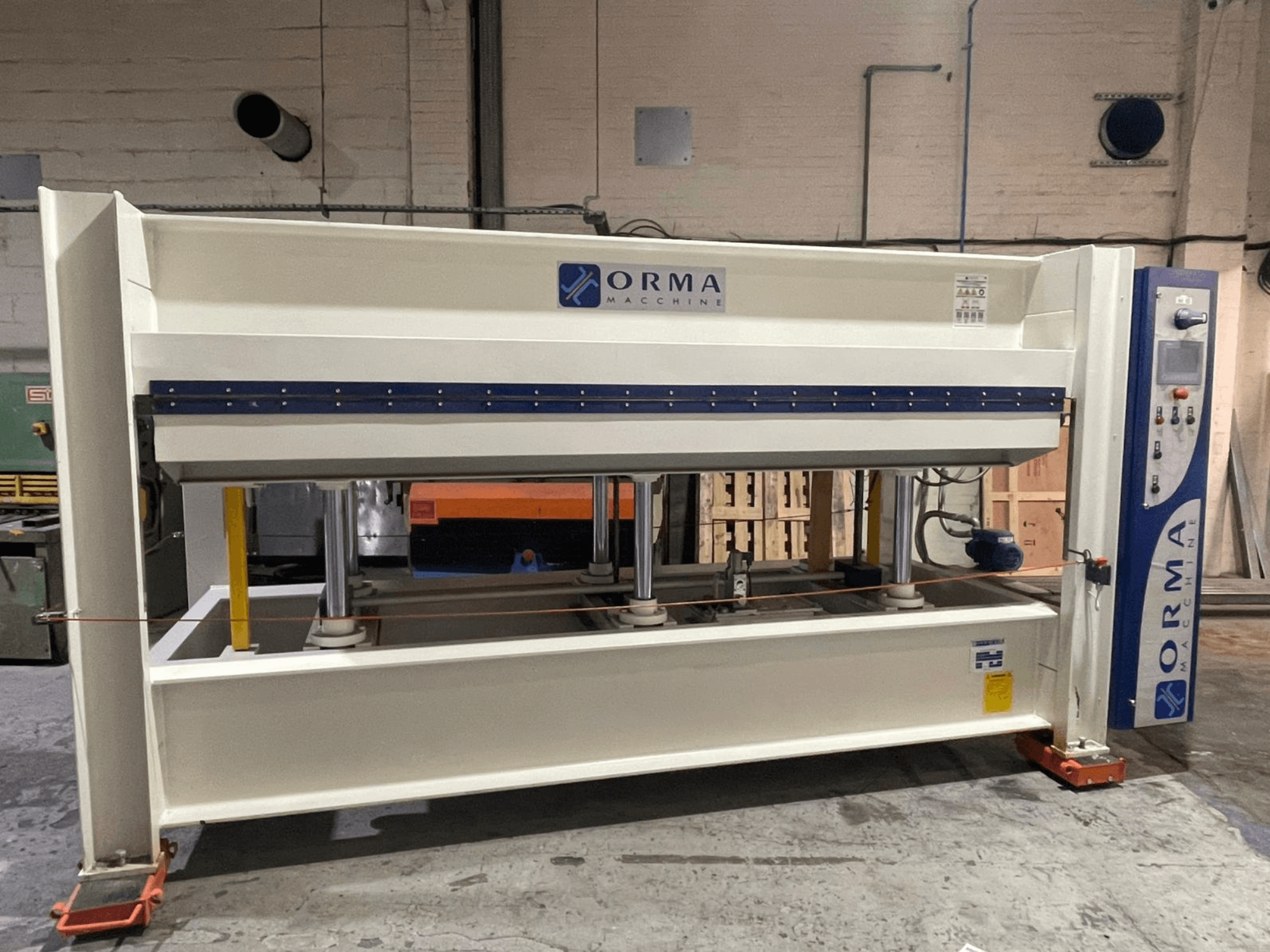 Pressa idraulica della macchina ORMA, vista frontale, con finitura argentata, pannello di controllo a destra e pistoni verticali per la pressatura.