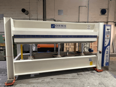 Pressa idraulica della macchina ORMA, vista frontale, con finitura argentata, pannello di controllo a destra e pistoni verticali per la pressatura.