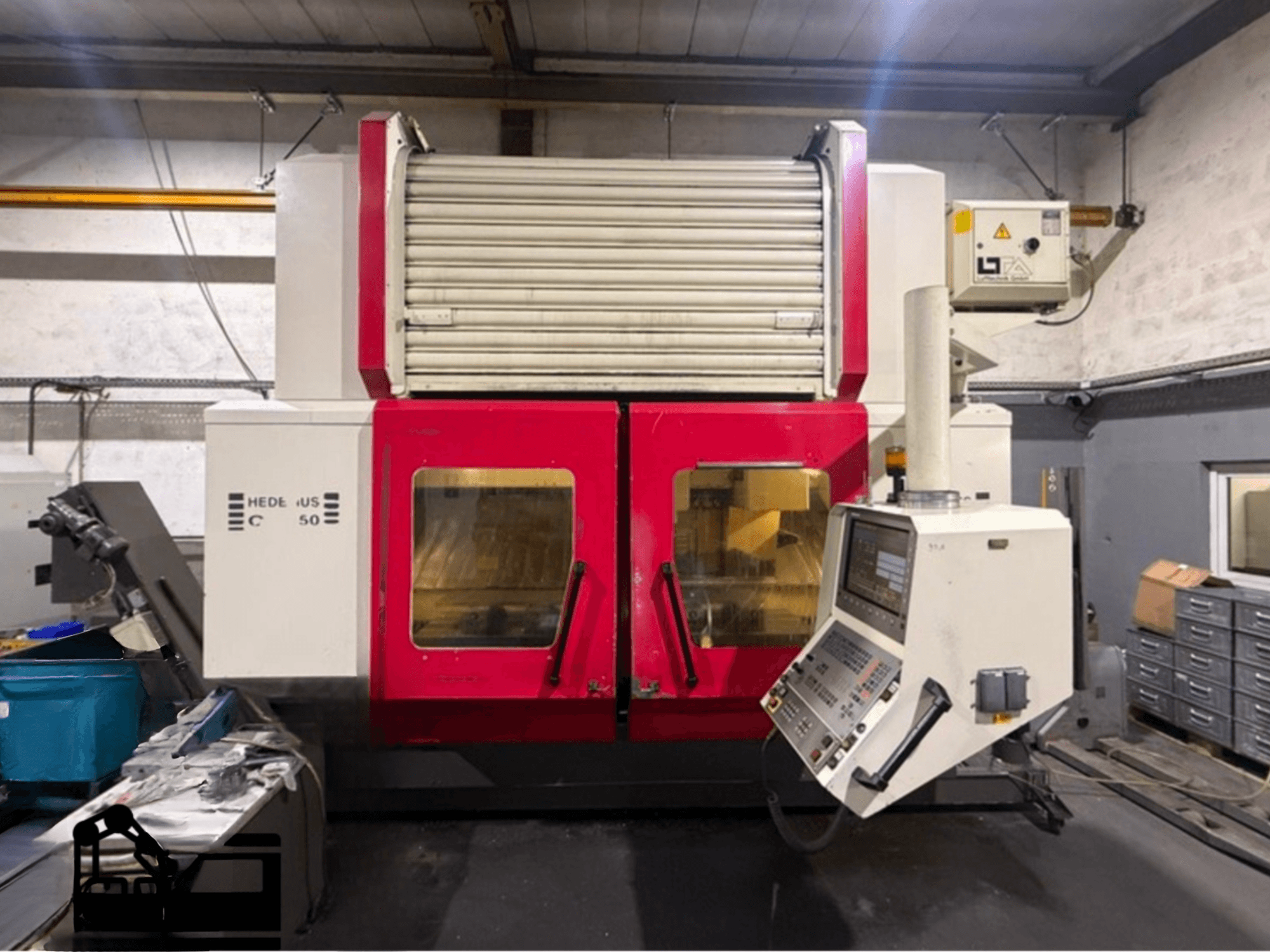 Centro di lavoro verticale HEDELIUS BC 50 in rosso e bianco con pannello di controllo, vista laterale, che mostra le caratteristiche operative.