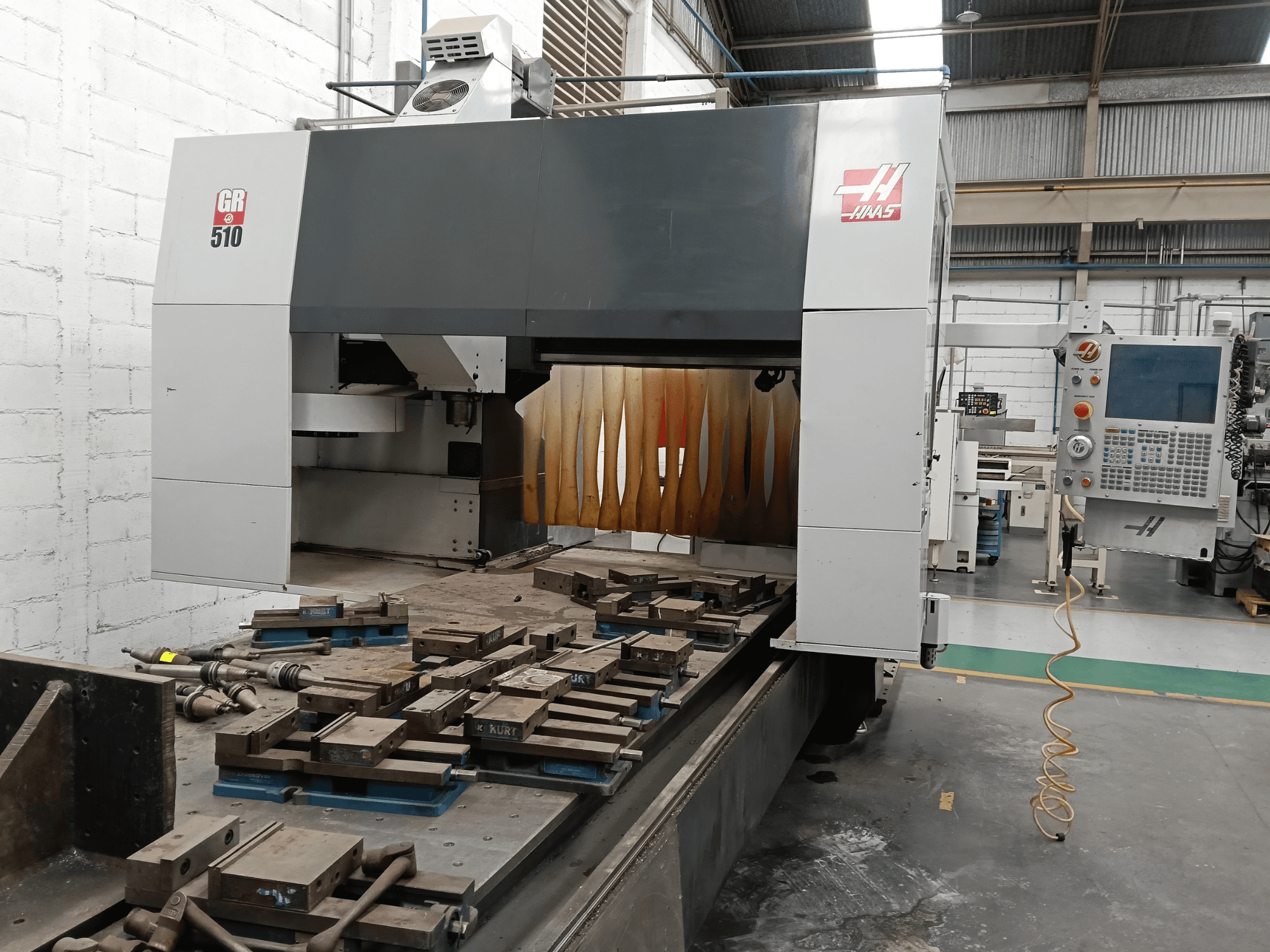 Vista frontale della fresatrice a portale HAAS GR-510, con il pannello di controllo e i pezzi lavorati sul piano di lavoro.