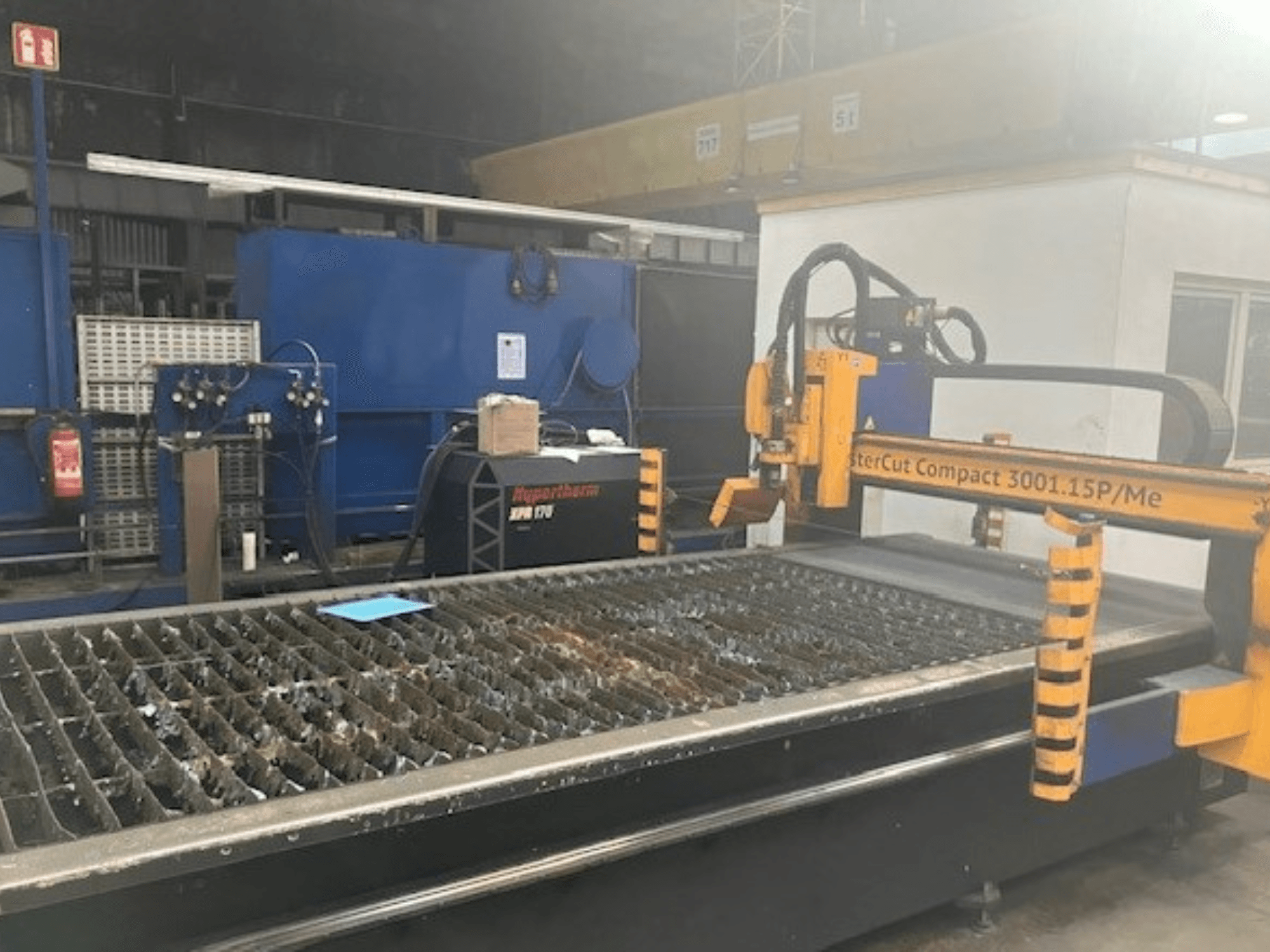 Macchina per il taglio al plasma Hypertherm MasterCut Compact 3001.15P/Me in vista laterale, con tavolo di taglio e pannello di controllo.