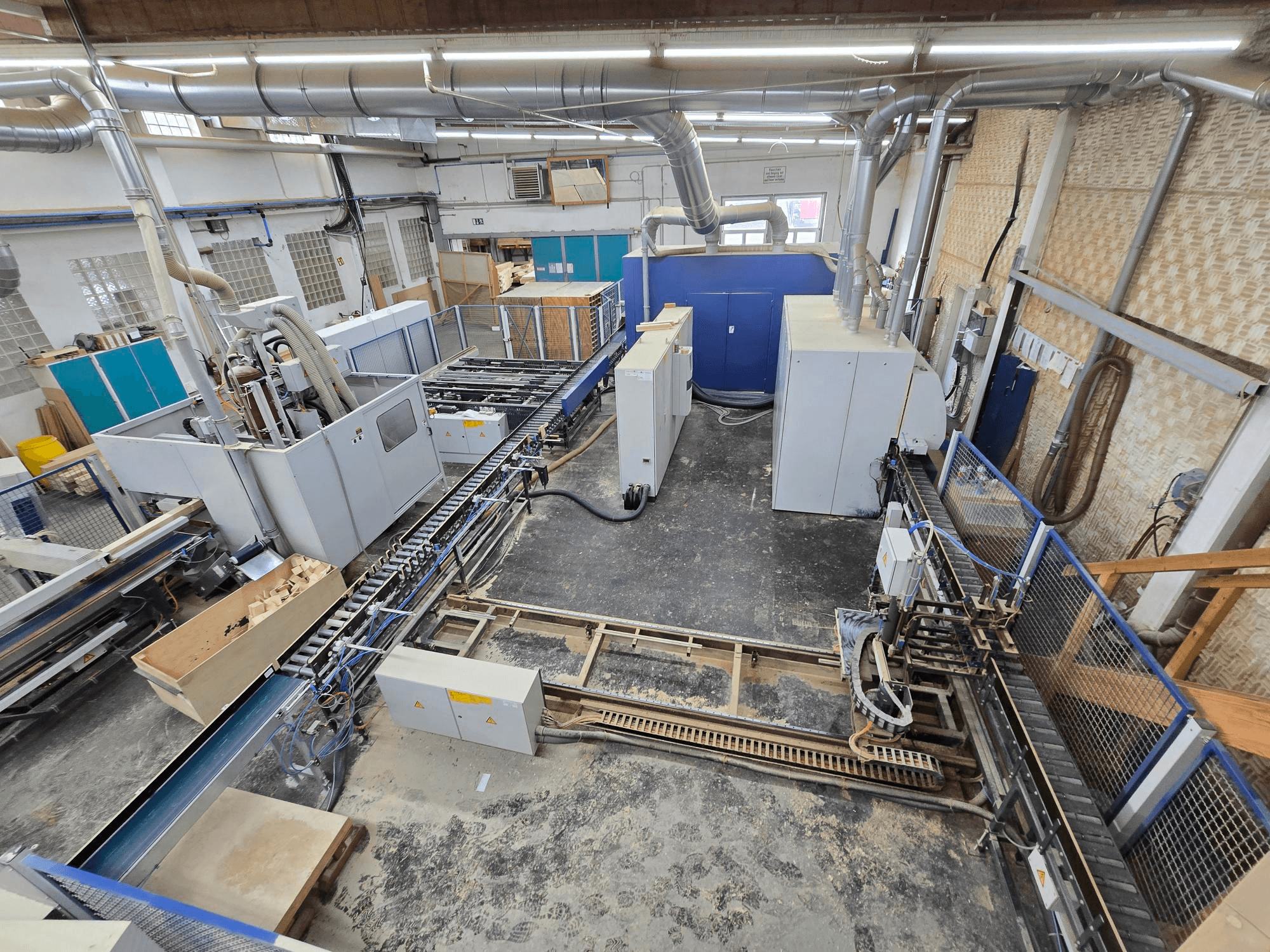 Linea completa di produzione di legno WEINIG DIMTER Unirex 2000 SPB in un ambiente industriale, vista dall'alto che mostra i macchinari e il sistema di trasporto.