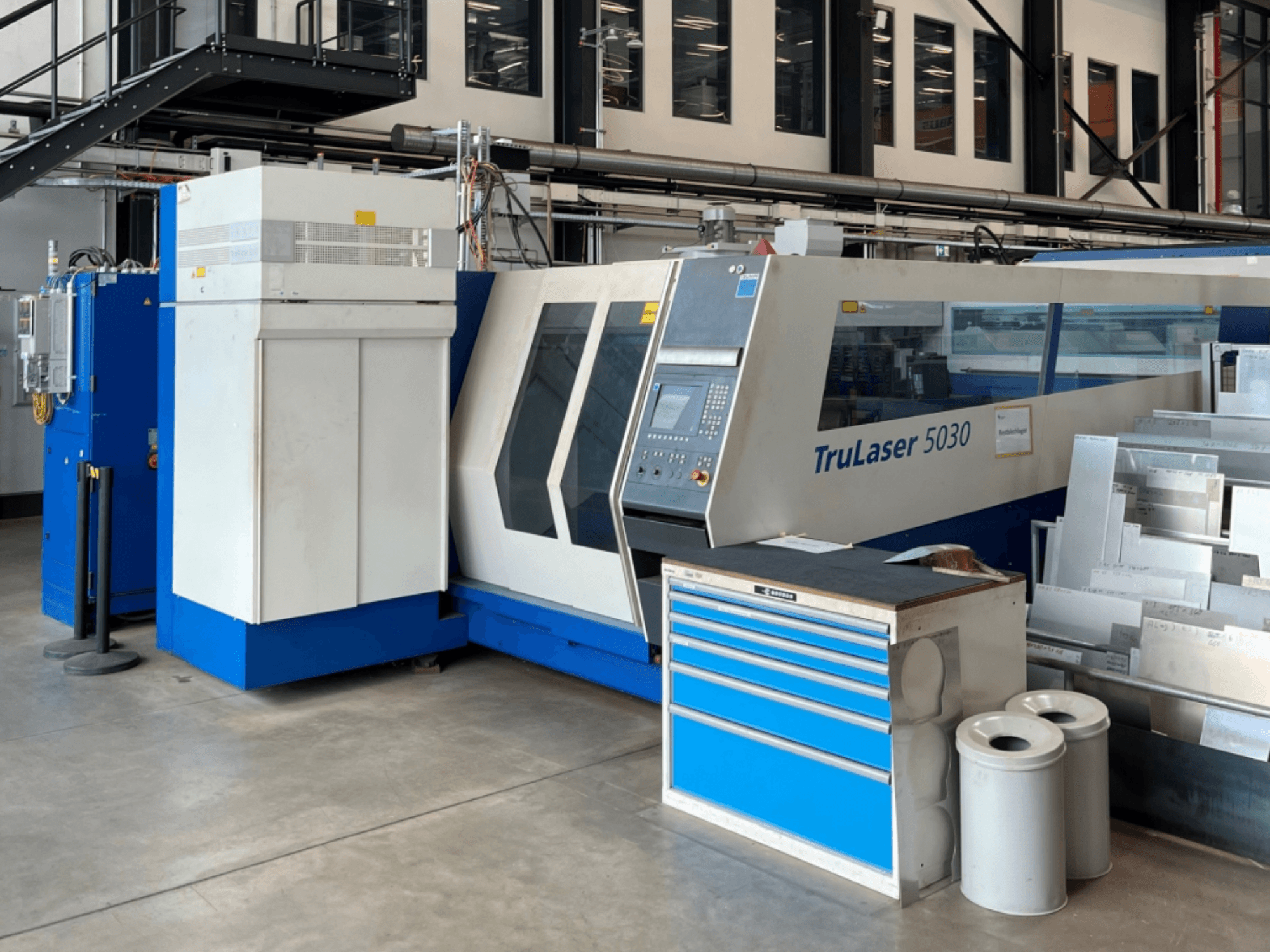 Macchina per il taglio laser a CO₂ TRUMPF TruLaser 5030 vista frontale, con pannello di controllo e banco di lavoro adiacente con lamiere.