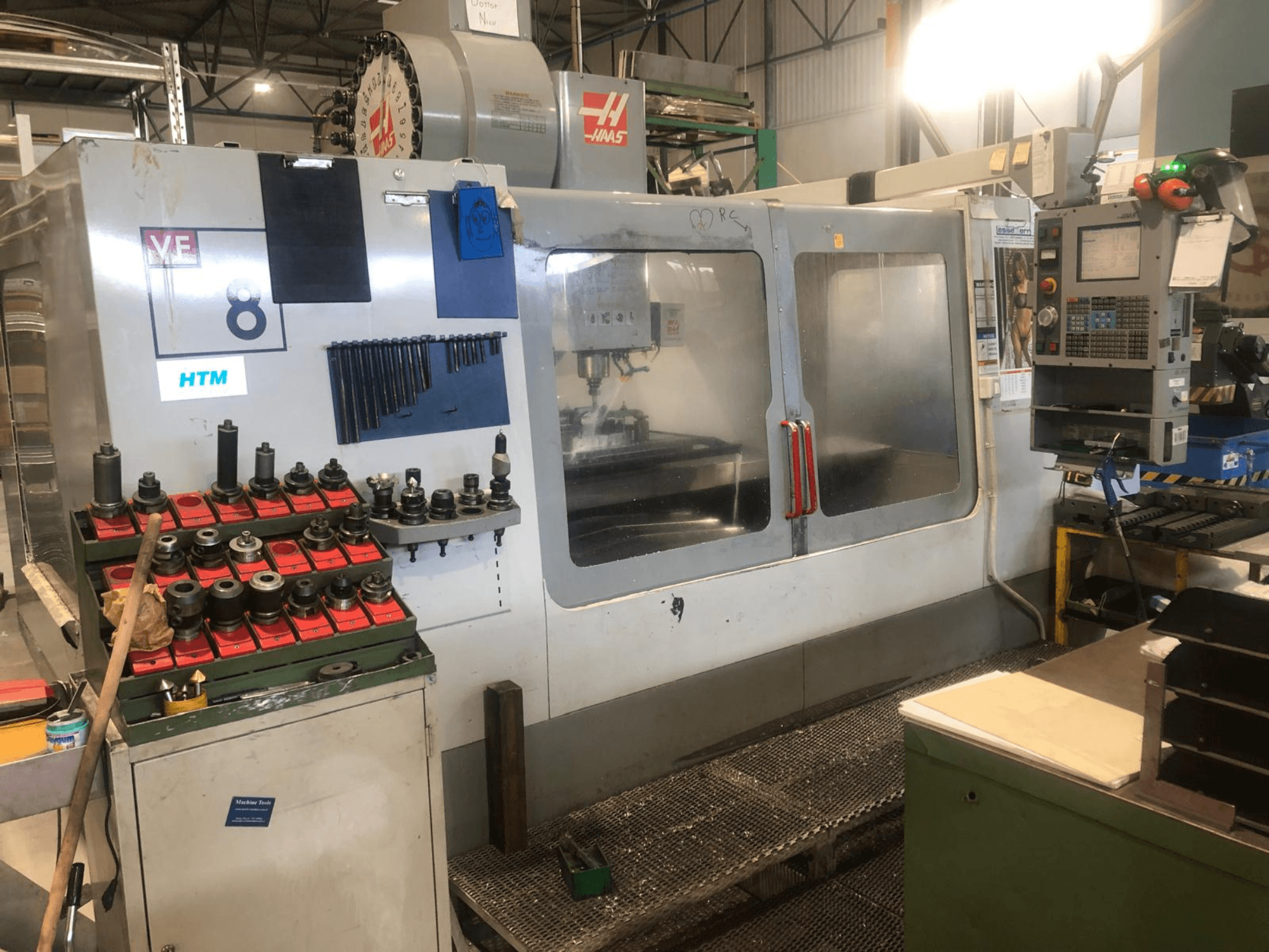 Macchina CNC Haas in un'officina, vista frontale; mostra utensili e comandi, con dettagli del modello visibili e portautensili organizzati.