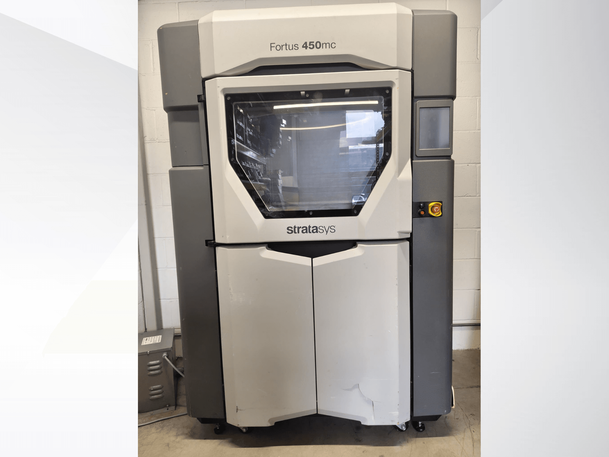 Macchina per la lavorazione della plastica Stratasys Fortus 450mc, vista frontale, caratterizzata da un'ampia finestra, un pannello di controllo e un design industriale.