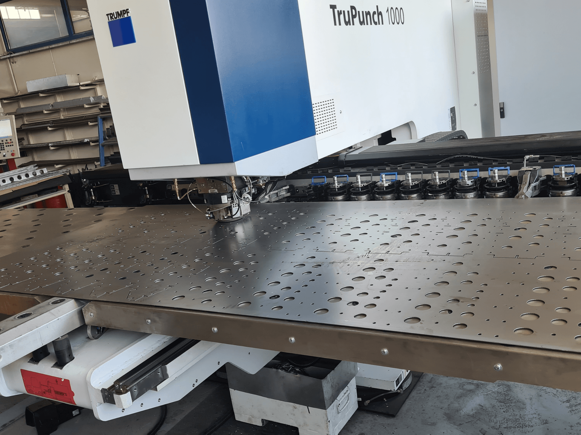 Punzonatrice CNC TRUMPF TruPunch 1000, vista frontale, con una lamiera forata e l'allestimento degli utensili.