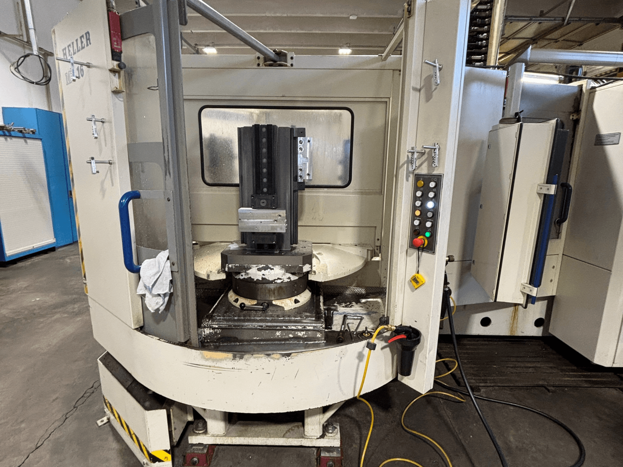 Centro di lavoro Heller, modello verticale, vista frontale che mostra il mandrino, il pannello di controllo e il piano di lavoro con l'attrezzatura collegata.