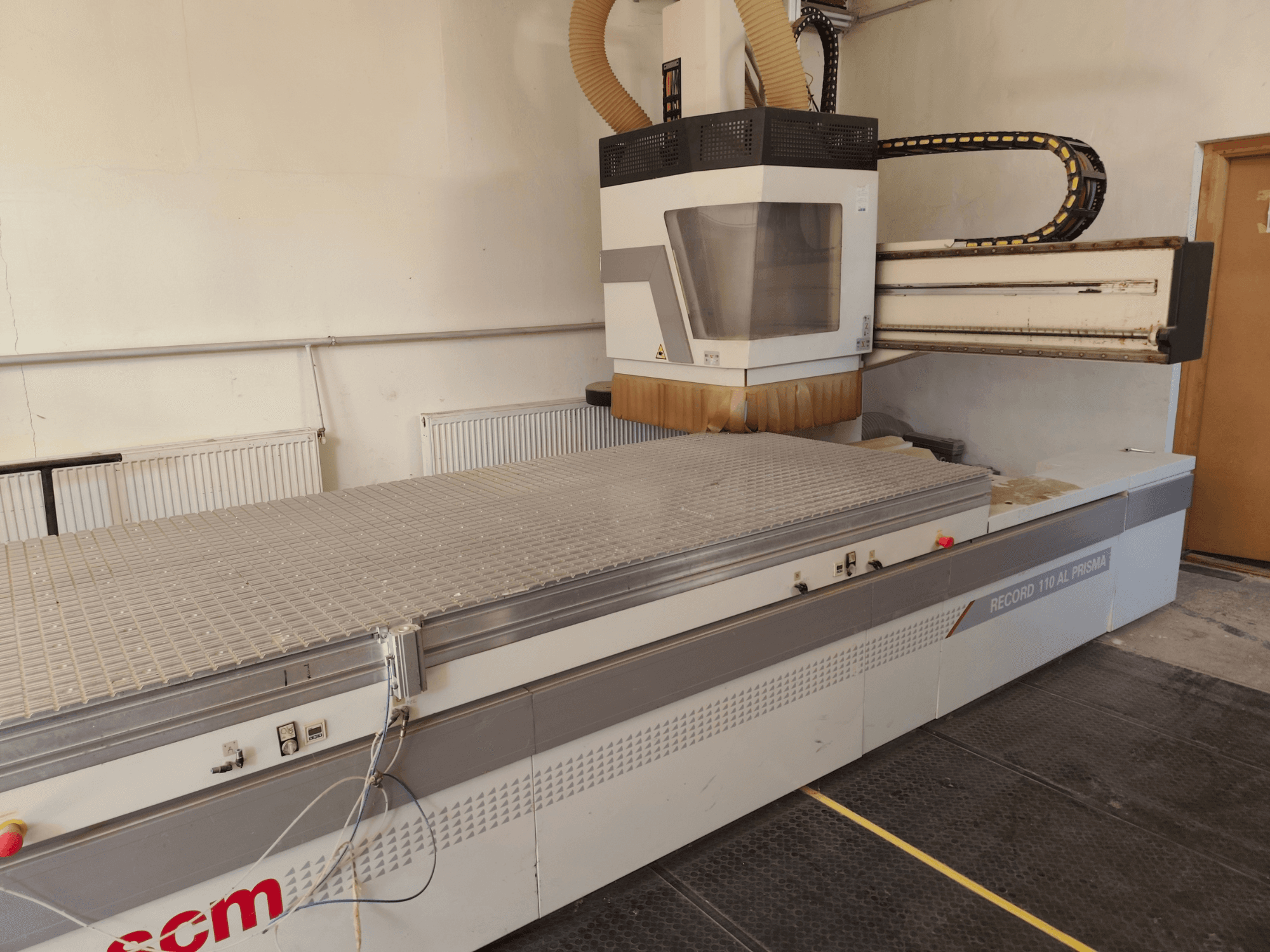 Centro di lavorazione del legno a controllo numerico SCM Record 110AL, vista laterale che mostra l'ampio piano di lavoro e la testa di fresatura.