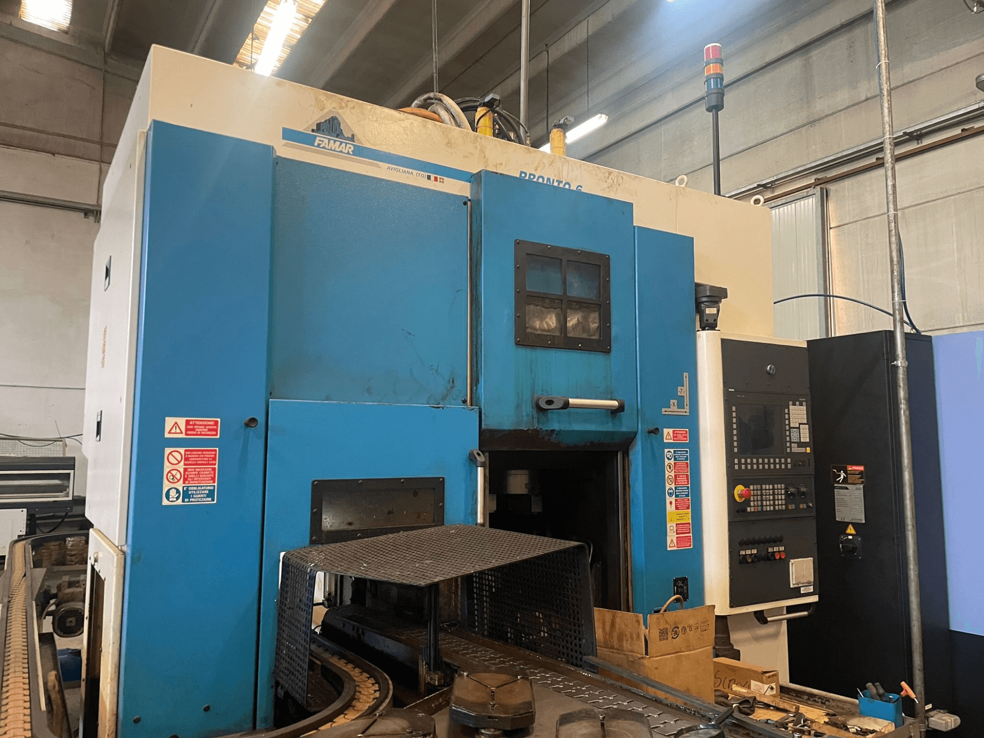 Tornio verticale Famar Pronto 6 in officina, vista laterale, con pannello di controllo, caratteristiche operative ed etichette di sicurezza.