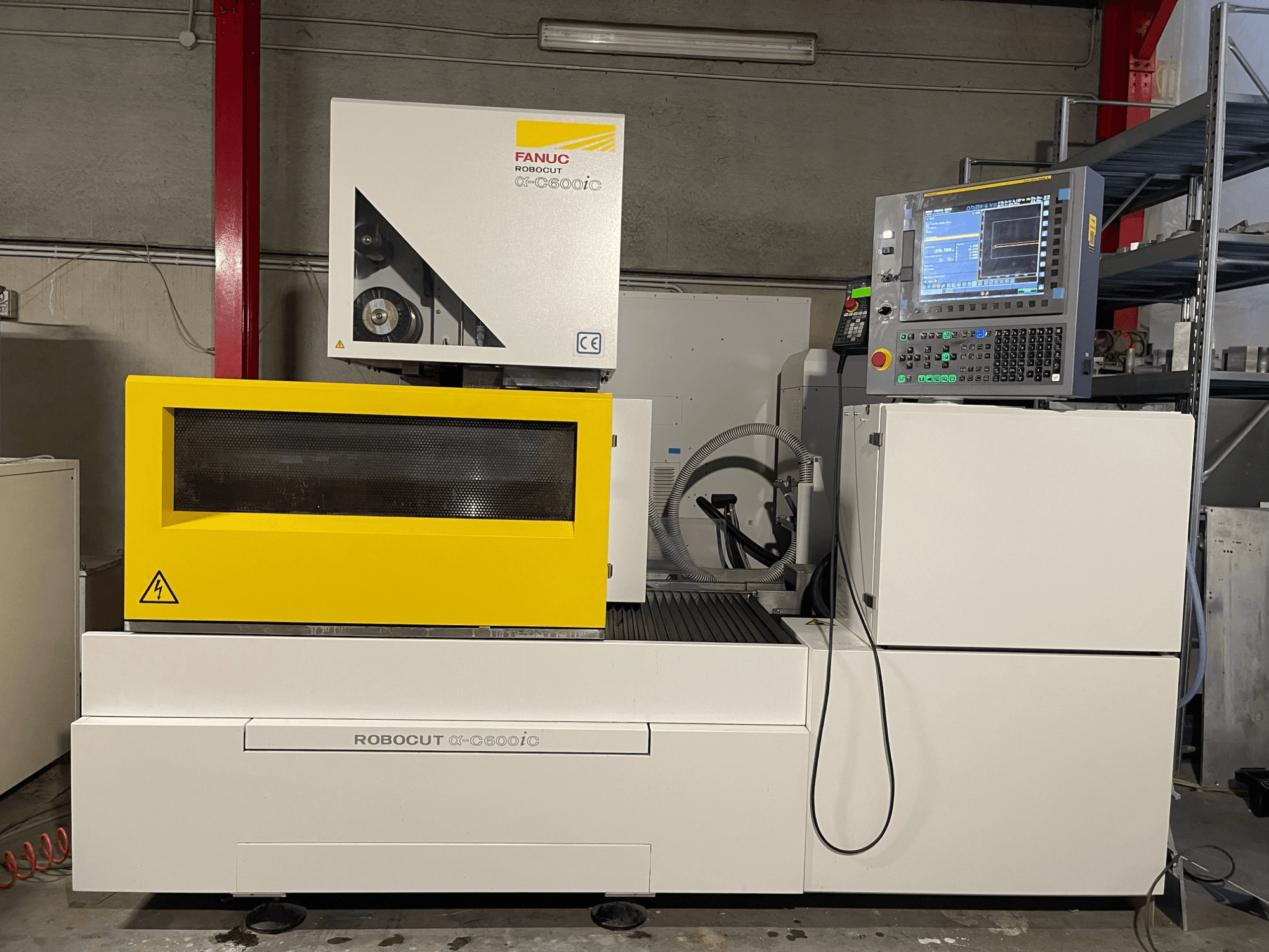 FANUC Robocut α-C600iC, vista laterale della macchina CNC con copertura di sicurezza gialla e pannello di controllo, che mostra la capacità di taglio di precisione.