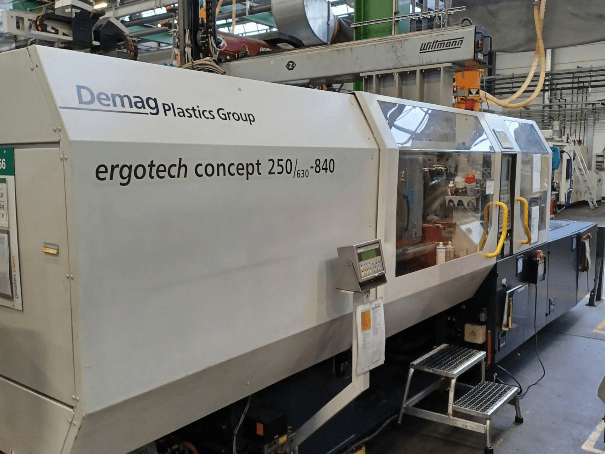 Macchina per lo stampaggio a iniezione Demag ergotech concept 250/630-840, vista frontale, con comandi digitali e coperture di sicurezza trasparenti.