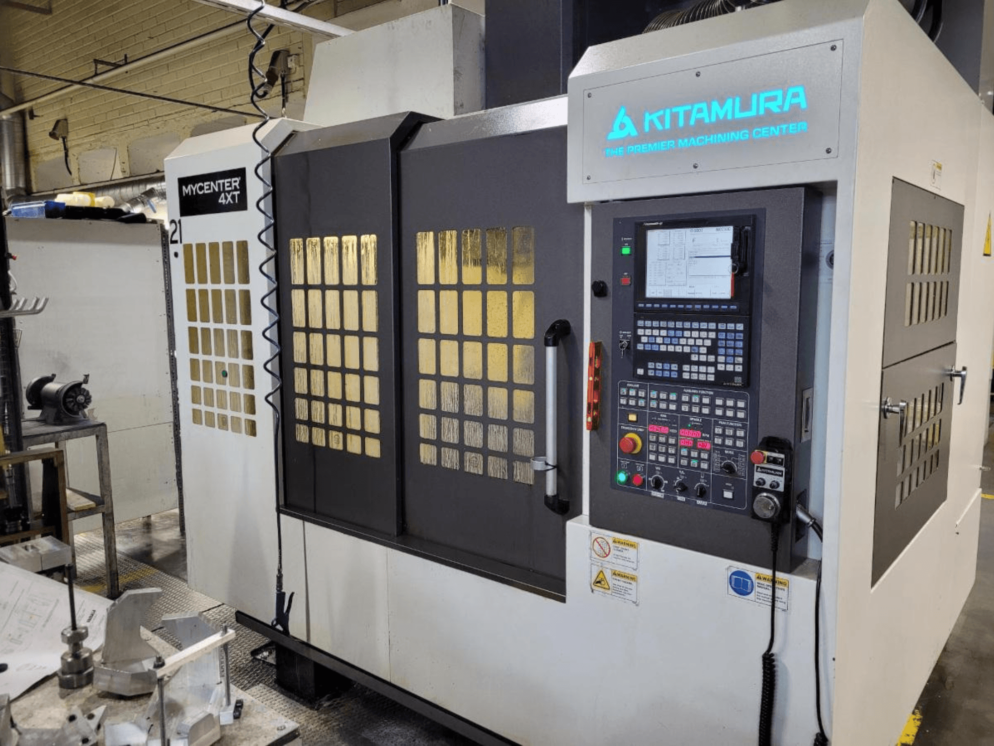 Vista verticale di un centro di lavoro Kitamura Mycenter-4XT, con pannello di controllo e marchio illuminato.