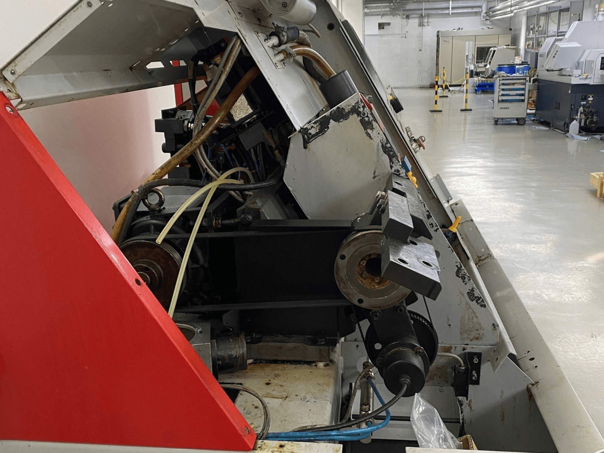 Tornio orizzontale EMCO Emcoturn 325, vista laterale che mostra i componenti di trasmissione e l'impianto idraulico in un contesto industriale.