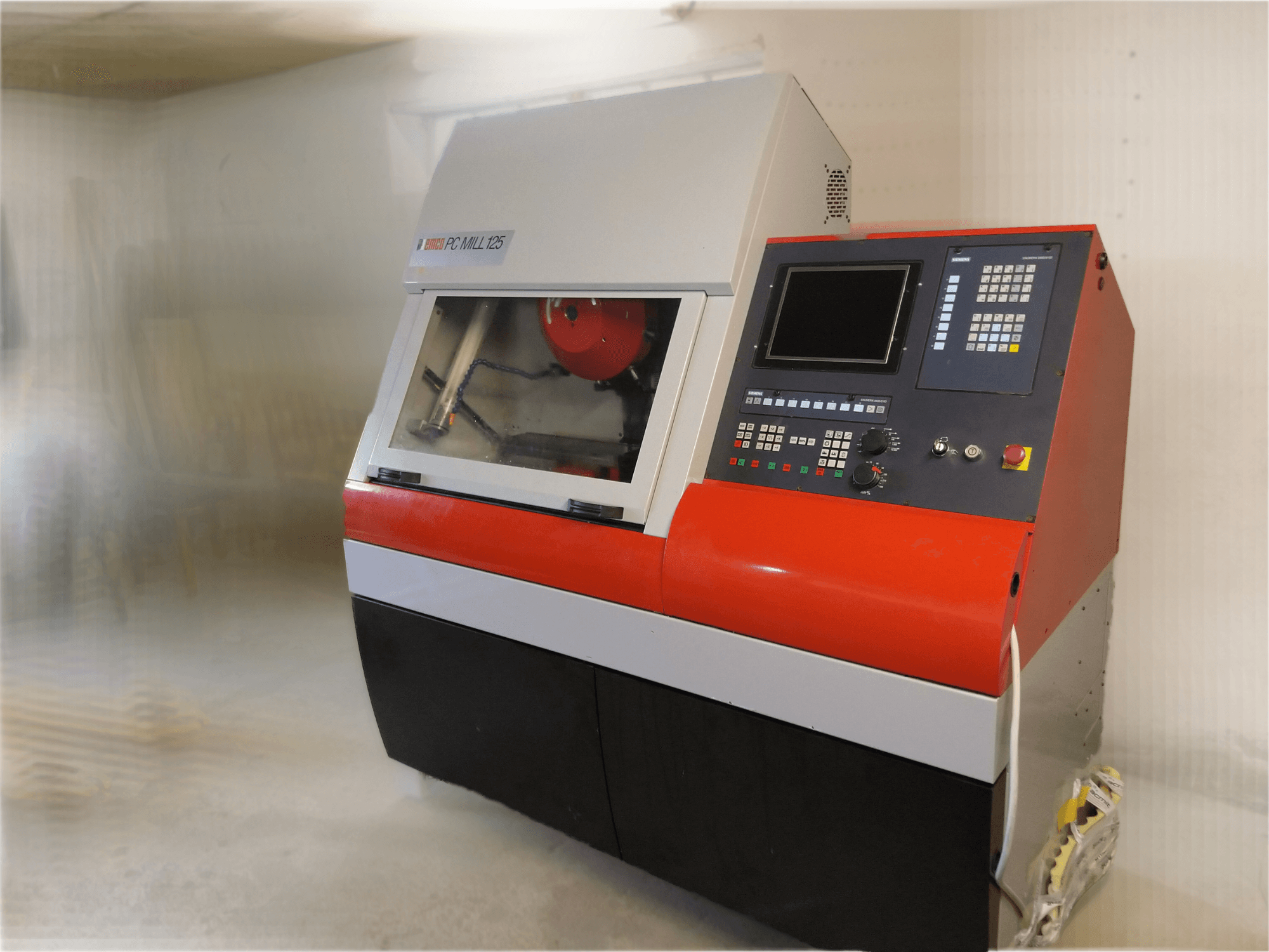 Centro di lavoro verticale EMCO PC MILL 125, vista frontale con pannello di controllo e area di lavorazione visibile.