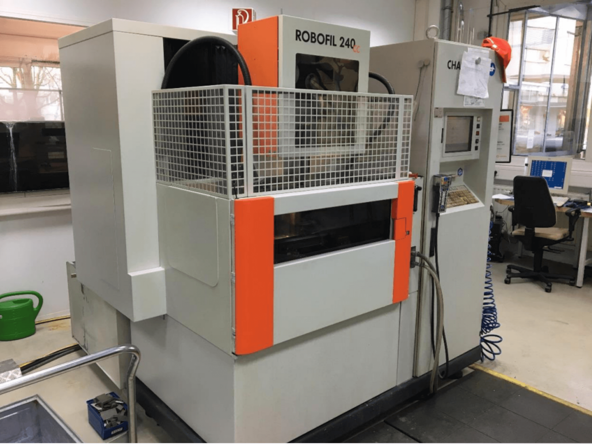 Vista frontale della macchina per elettroerosione a filo CHARMILLES ROBOFIL 240 CC, dotata di griglia di protezione e pannello di comando, situata in un'officina.