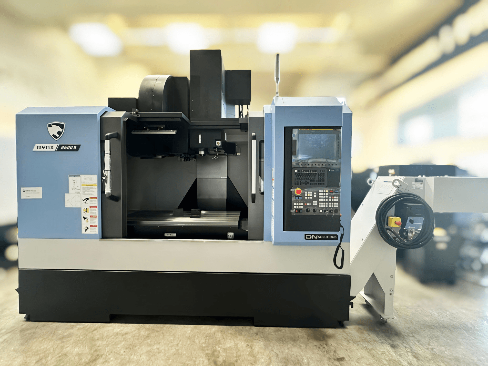 Centro di lavoro verticale DN SOLUTIONS MYNX 6500 II, vista frontale, con pannello di controllo e area di lavorazione aperta.