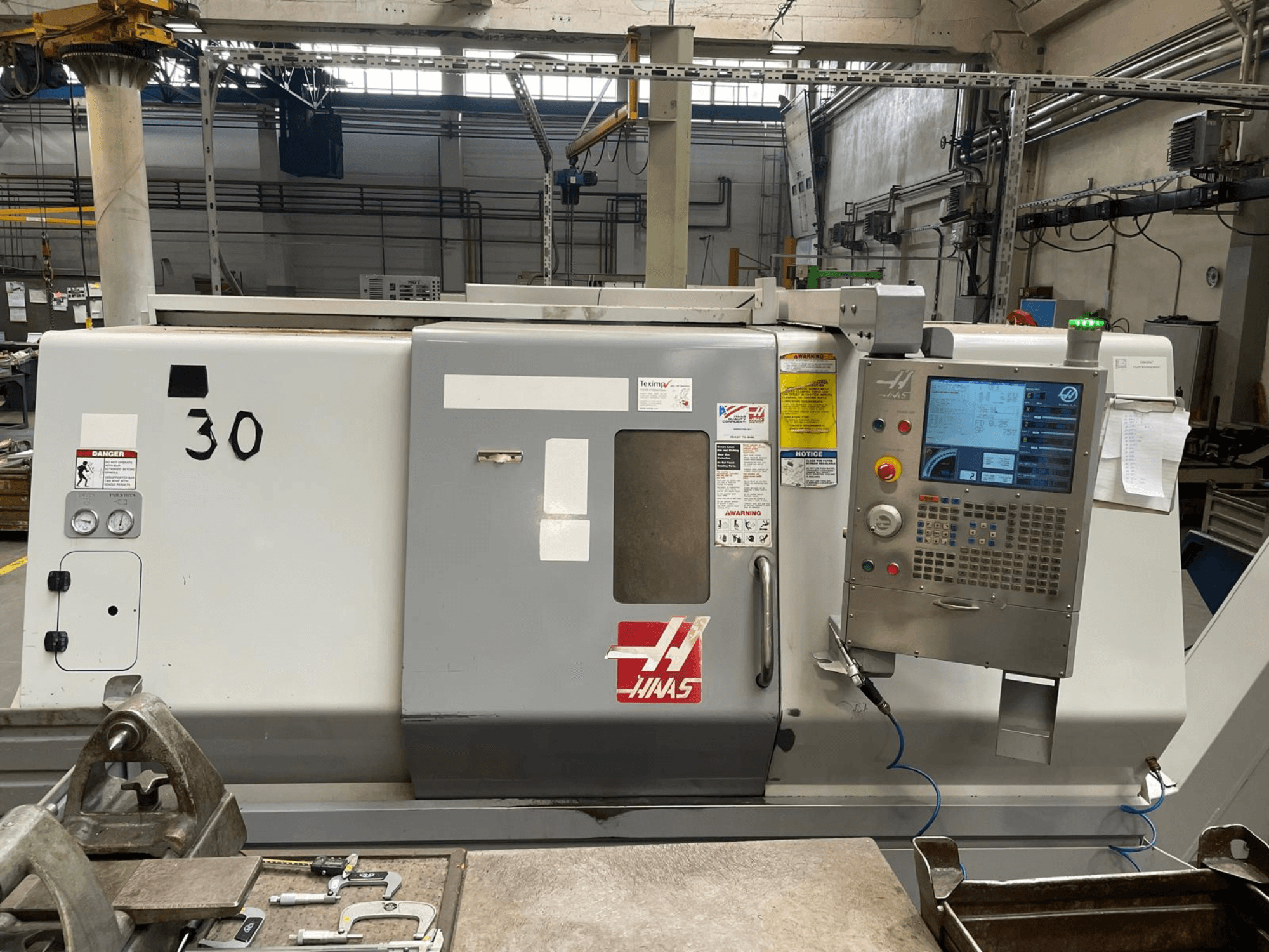 Vista frontale del tornio orizzontale Haas SL-30THE, con pannello di controllo digitale, etichette di avvertenza e numero di modello 30.