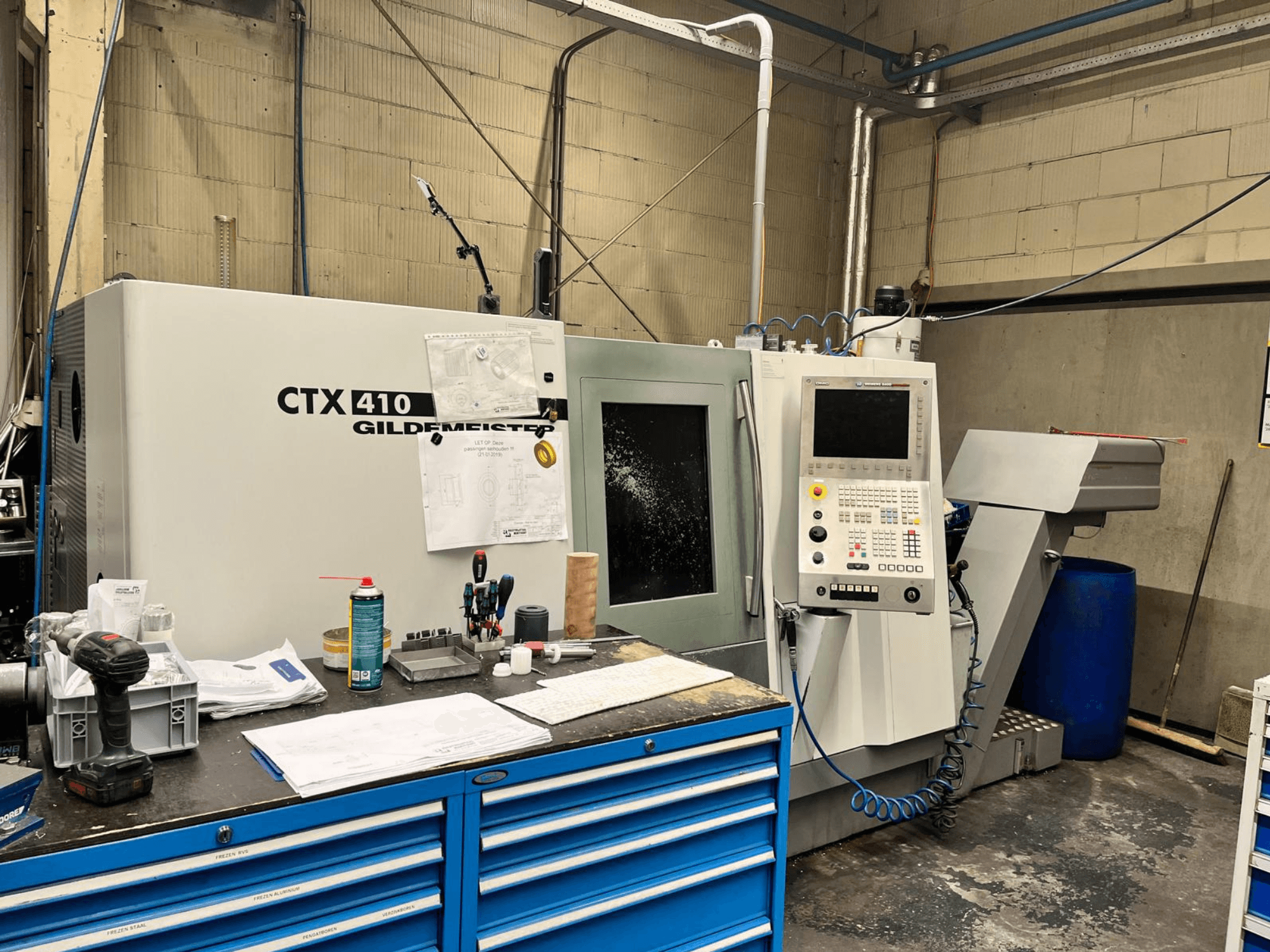 Macchina CNC Gildemeister CTX 410 in un'officina, vista frontale, con pannello di controllo e vari utensili su un banco di lavoro.