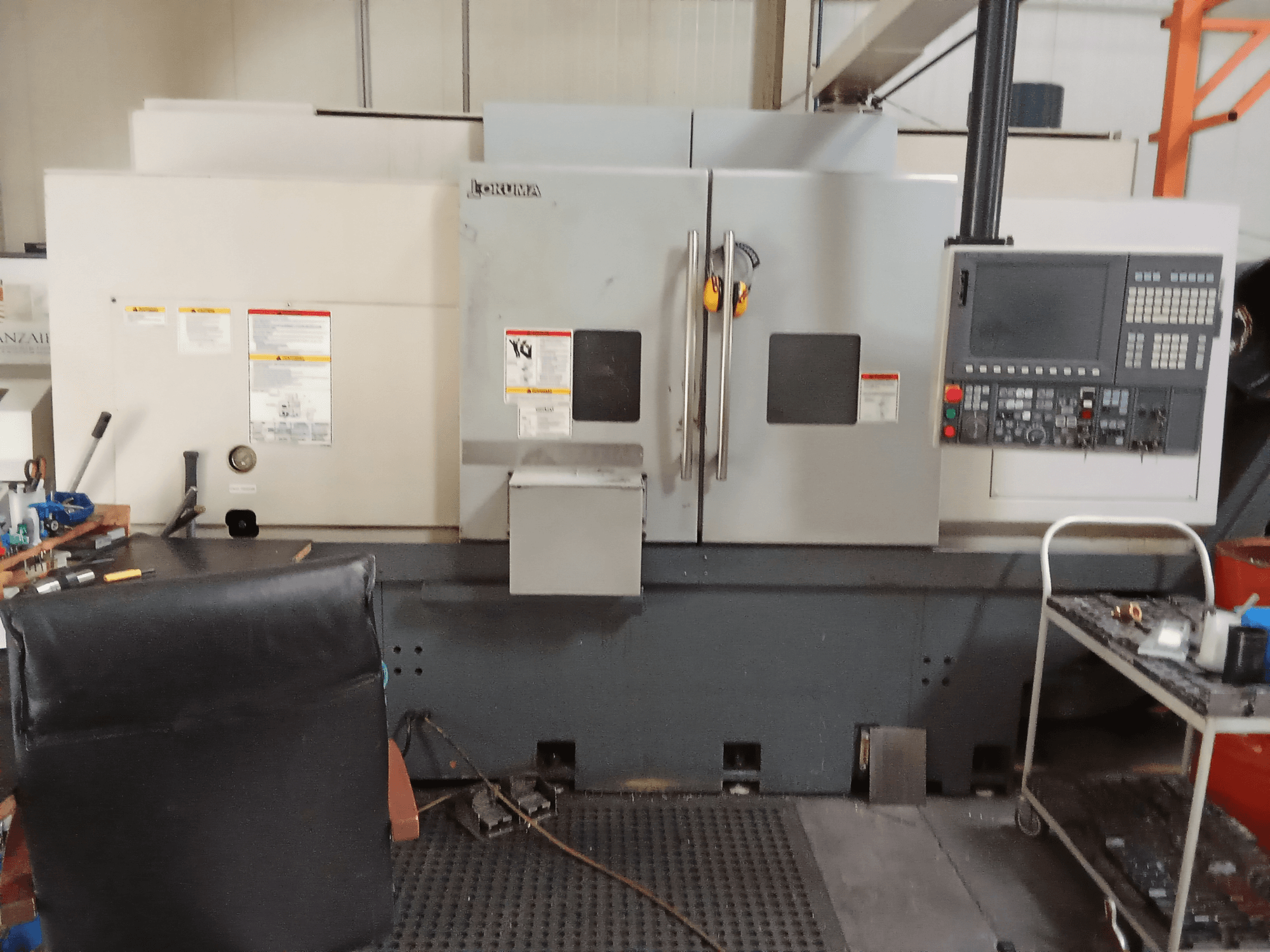 Tornio orizzontale Okuma Genos L300 E-M in vista frontale, con pannello di controllo e doppia porta, in un ambiente di officina.