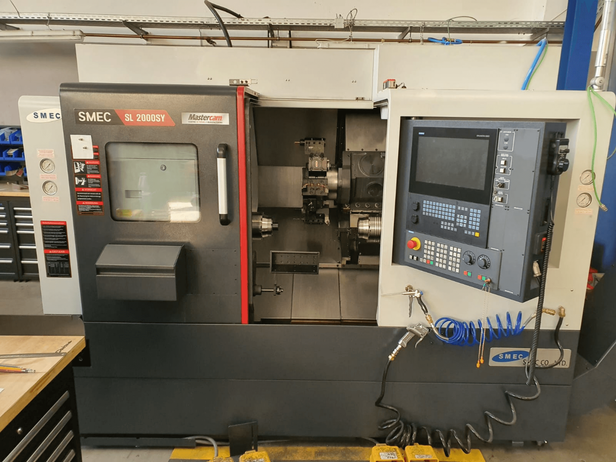 Tornio orizzontale SMEC SL2000SY visto frontalmente, con pannello di controllo, schermo di visualizzazione e portautensili.