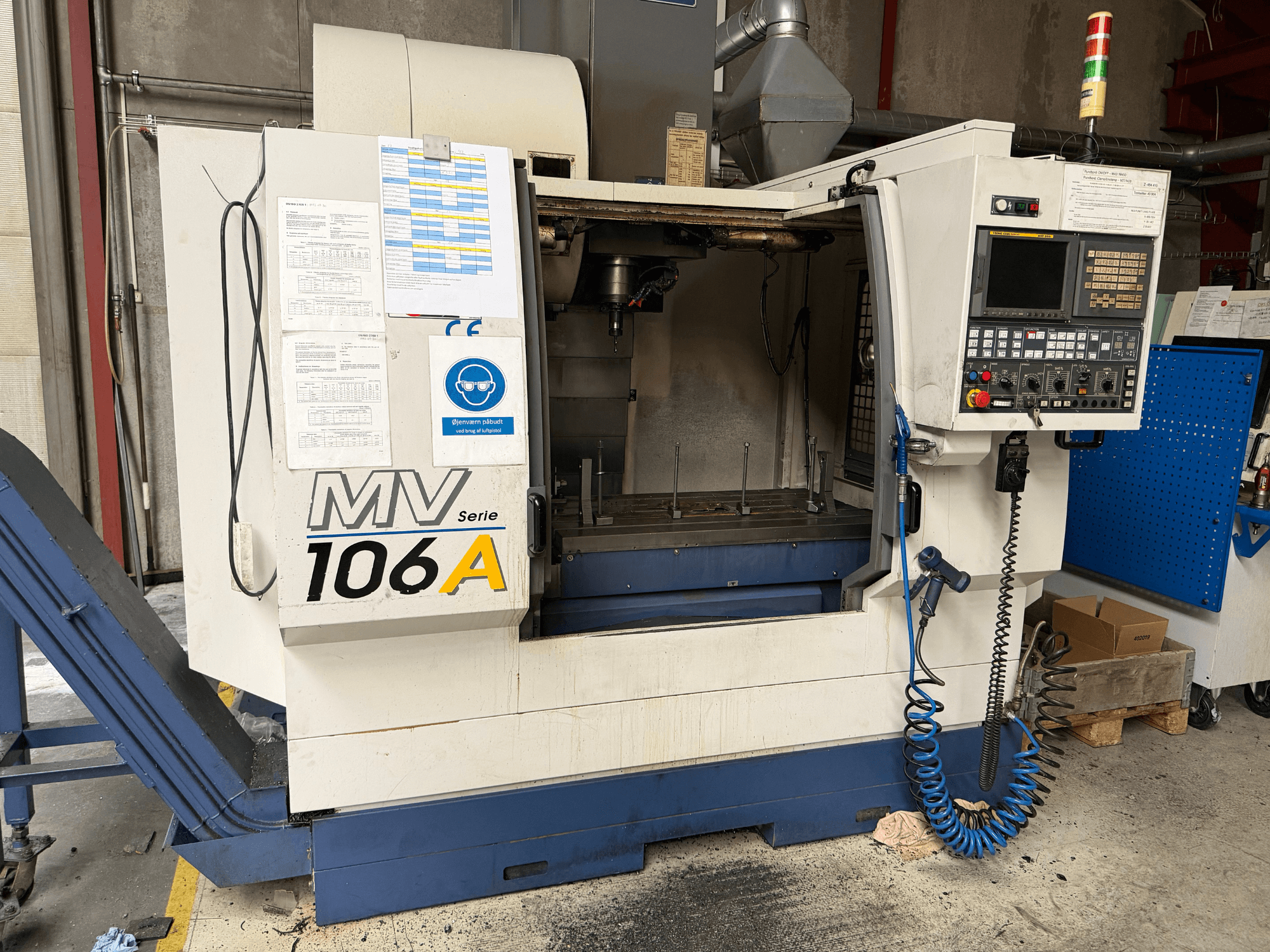 Centro di lavorazione verticale YCM MV106A, vista frontale con pannello di comando e area di lavoro, corredato di documentazione tecnica.