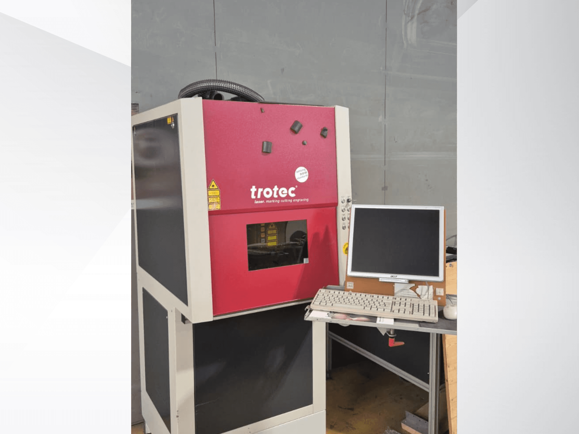 Stazione di lavoro laser Trotec rossa vista frontalmente, dotata di monitor e tastiera.