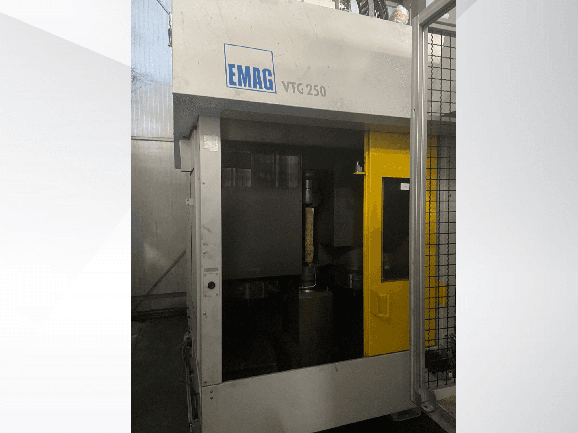 Centro di lavoro verticale EMAG VTC 250 in vista frontale, con porta gialla e utensile da taglio visibile all'interno della camera.