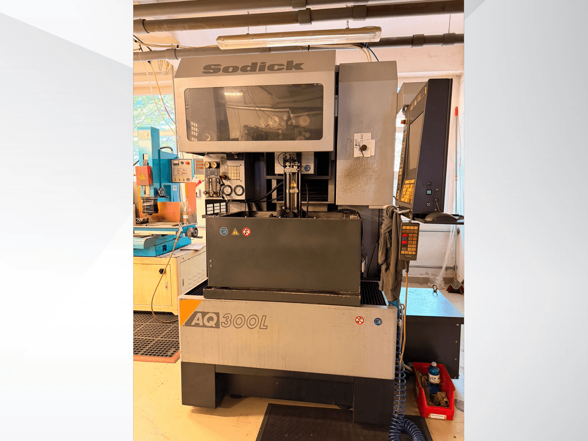Macchina per elettroerosione a filo Sodick AQ300L, vista frontale, con pannello di controllo, area di lavoro e indicatori di sicurezza ben visibili.