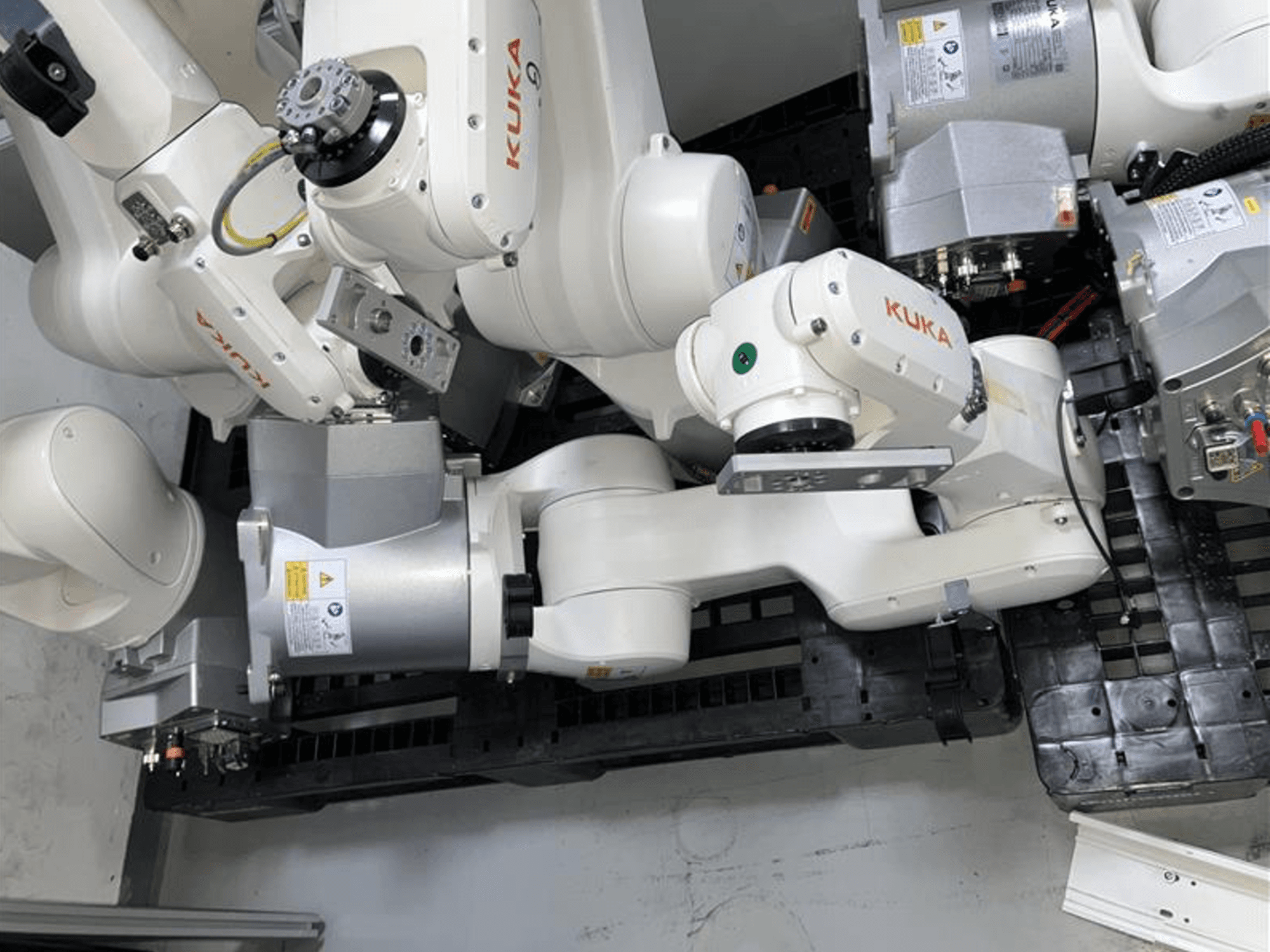 Braccio robotico KUKA KR 6 R900 CR in vista dall'alto, con articolazioni e motori multipli, montato su una base nera con cavi.