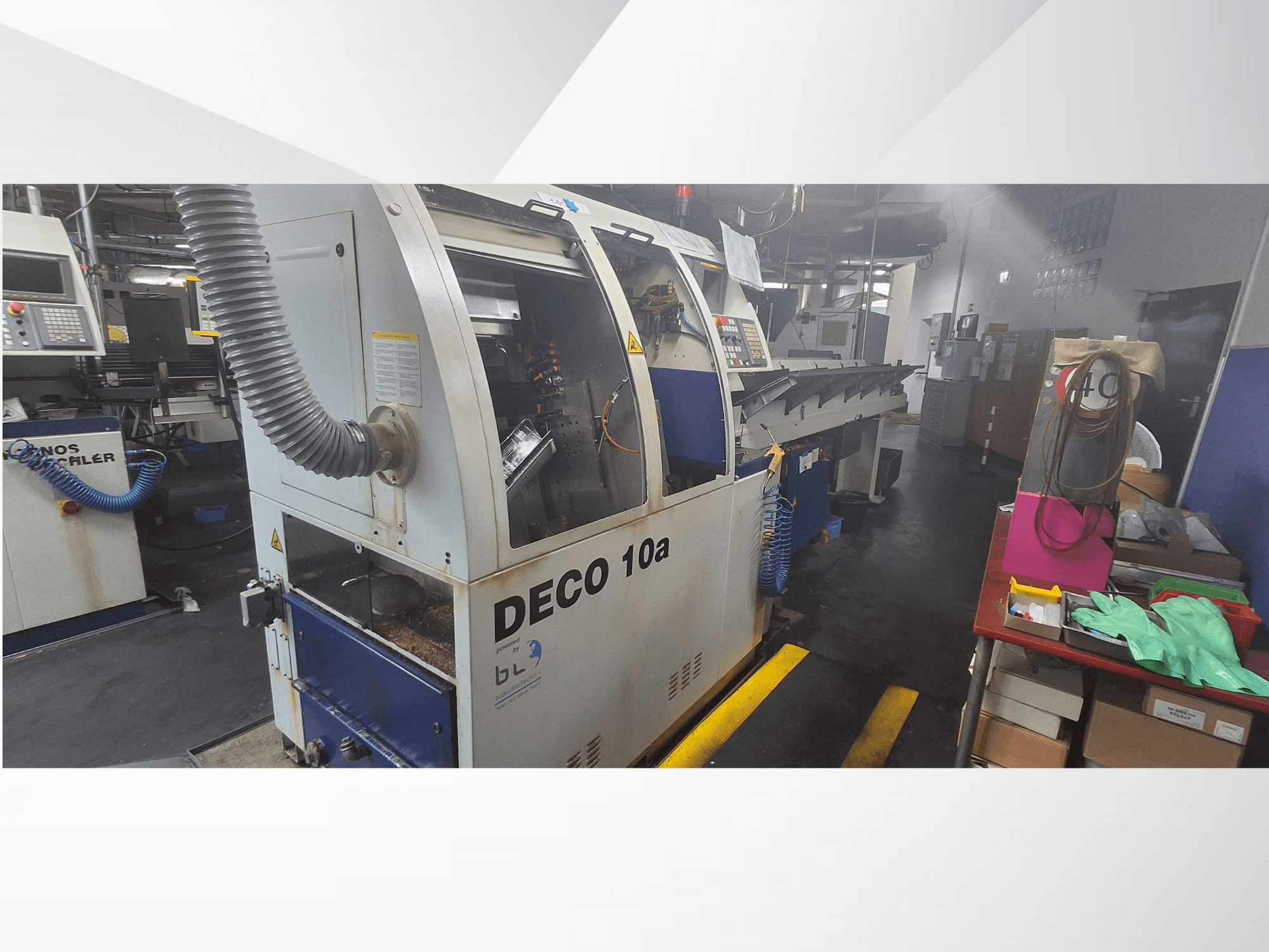 Macchina a controllo numerico DECO 10a in un'officina, vista frontale; dispone di un pannello di controllo e di un sistema di aspirazione delle polveri, con il banco di lavoro vicino.