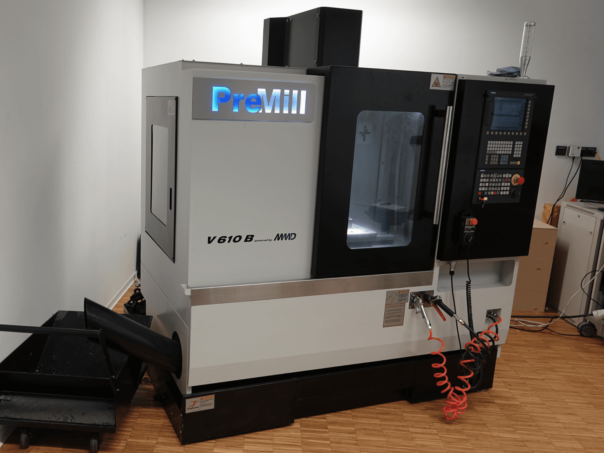 Centro di lavorazione verticale PreMill V 610 B, vista frontale, con pannello di controllo, sistema di raffreddamento e tubi dell'aria collegati.