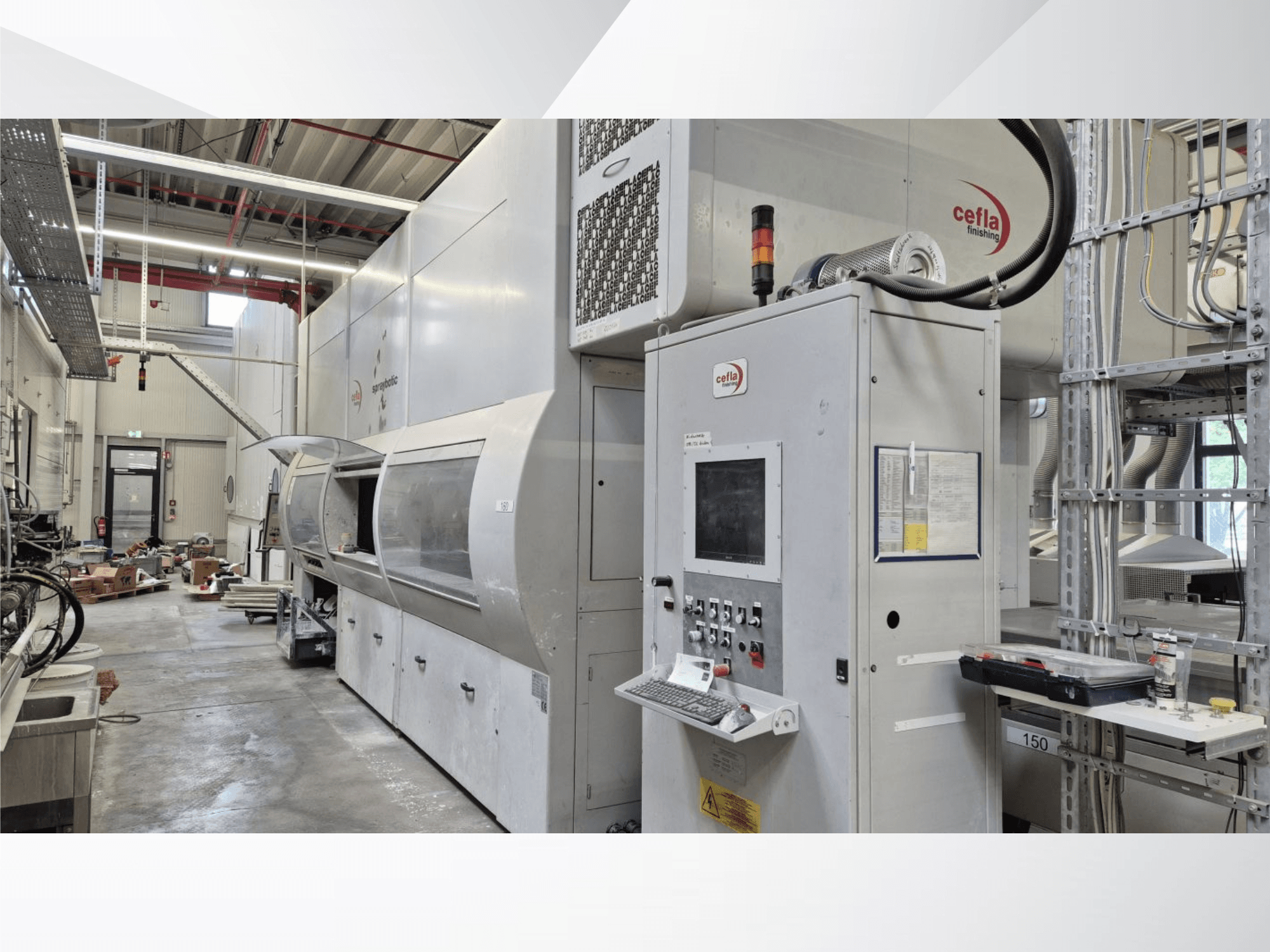 Linea di produzione Cefla Spraybotic MD in un’officina, vista frontale che mostra il pannello di controllo e la camera di spruzzatura con copertura trasparente.