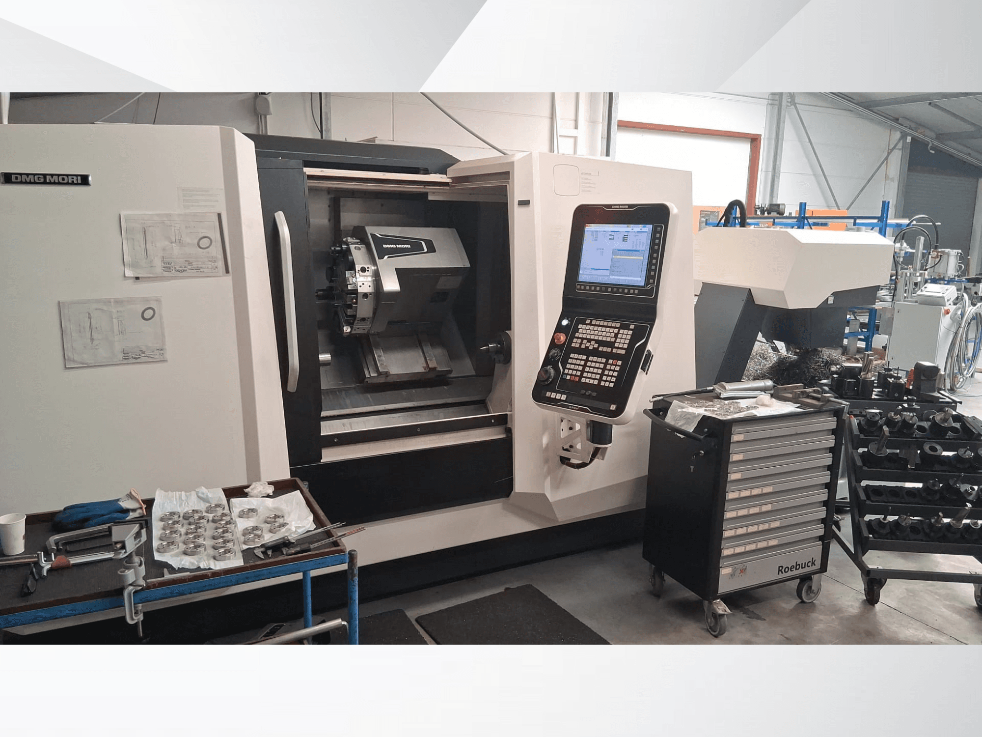 Tornio orizzontale DMG MORI CLX450 visto frontalmente, con pannello di controllo, area di lavoro, utensili e parti metalliche.