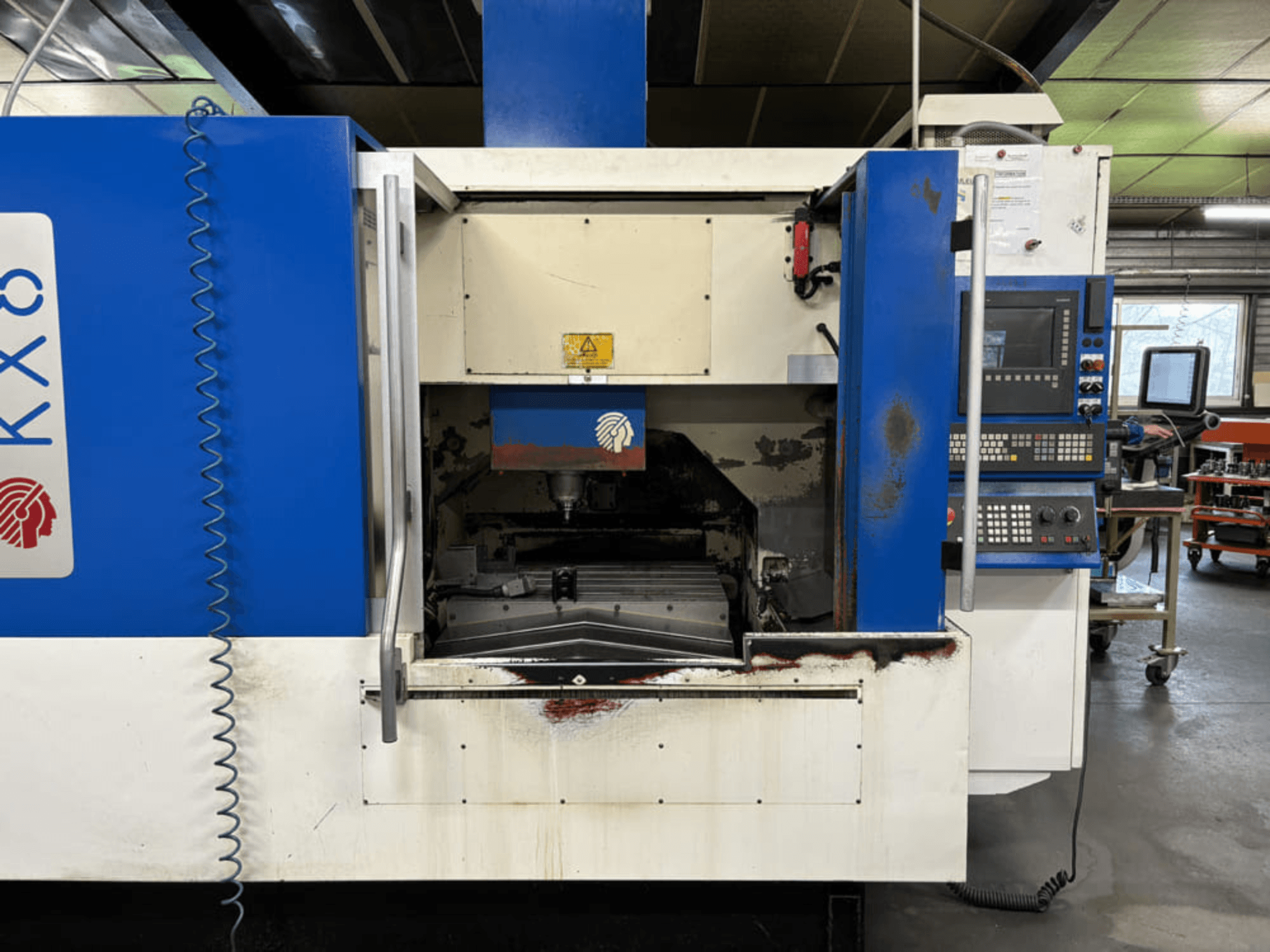 Centro di lavorazione verticale Huron KX8, vista frontale, con porta aperta, area di lavorazione e pannello di controllo con tastiera.