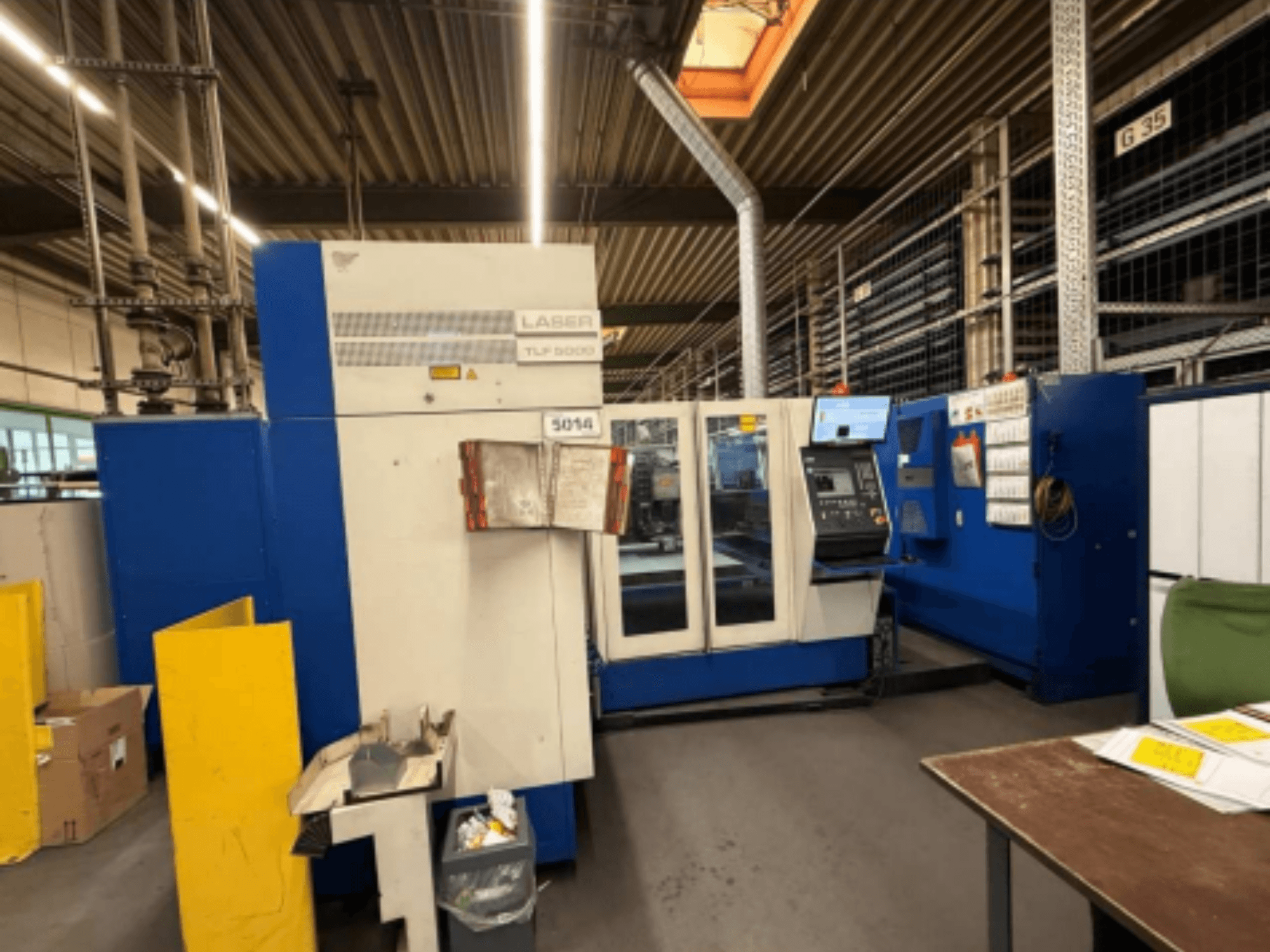 Vista frontale della macchina da taglio laser CO2 TRUMPF Trumatic L 3050, che mostra il pannello di controllo e le caratteristiche operative in un'officina.