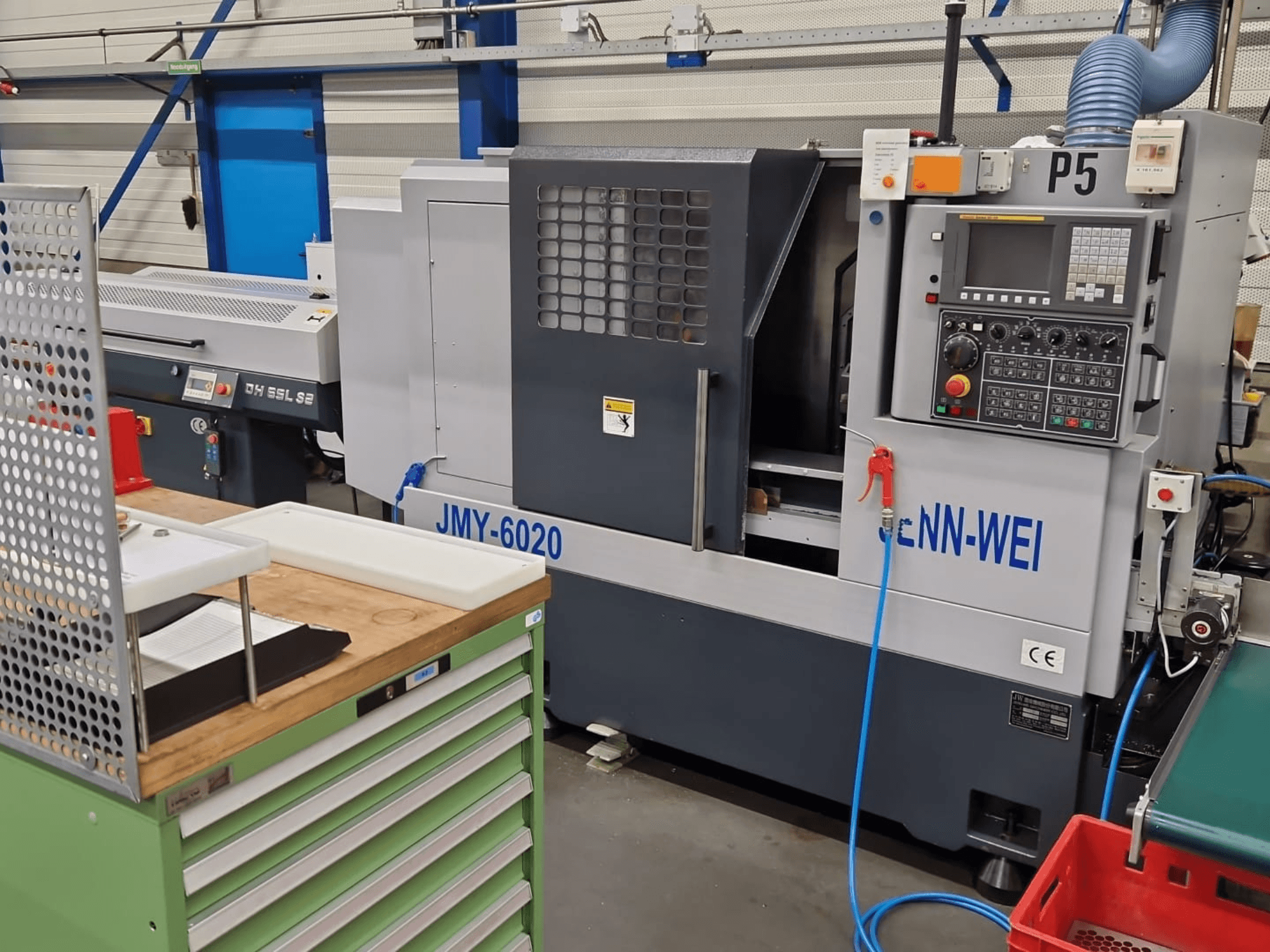 Tornio CNC, modello JMY-6020 di cNN-WEI, visto dal davanti. Pannello di controllo, arresto di emergenza e linea del refrigerante.