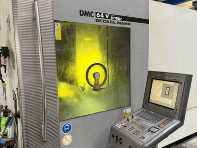 DMC 64 V linear di Deckel Maho, vista frontale della macchina con pannello di controllo e finestra gialla che mostra i meccanismi interni.