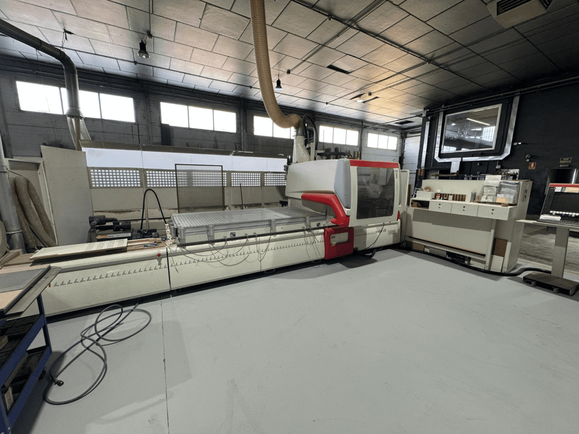 Macchina CNC in officina, vista frontale con accenti rossi, dotata di pannello di controllo e piano di lavoro, per il taglio di precisione.