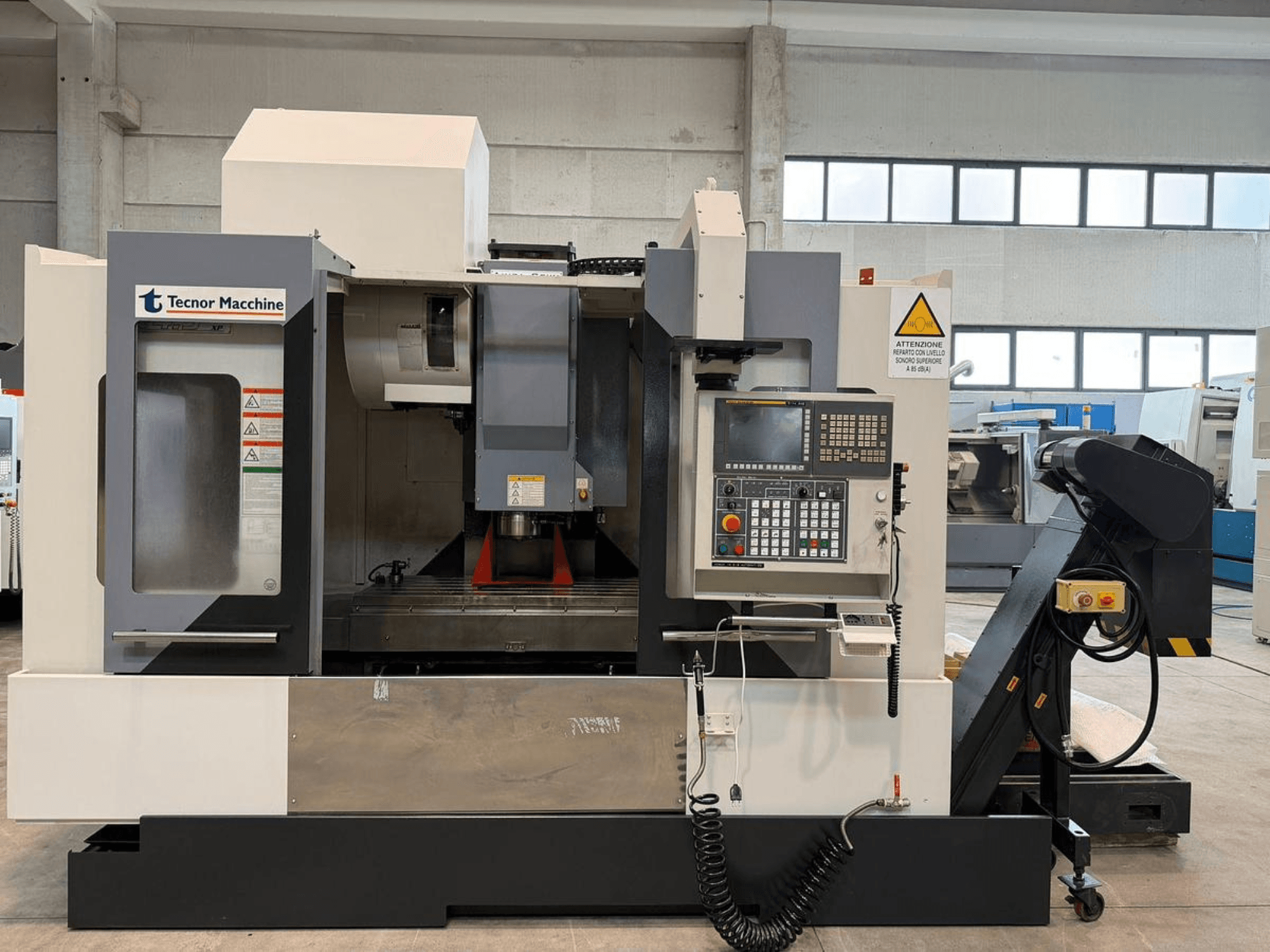 Fresatrice CNC Tecnor Machine, vista frontale, con pannello di controllo con pulsanti, etichette di avvertimento e portautensili.