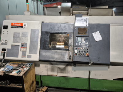 Tornio Mazak Integrex 200Y, vista frontale, con pannello di controllo e utensili su un banco. Indicatori e schermo del display visibili.