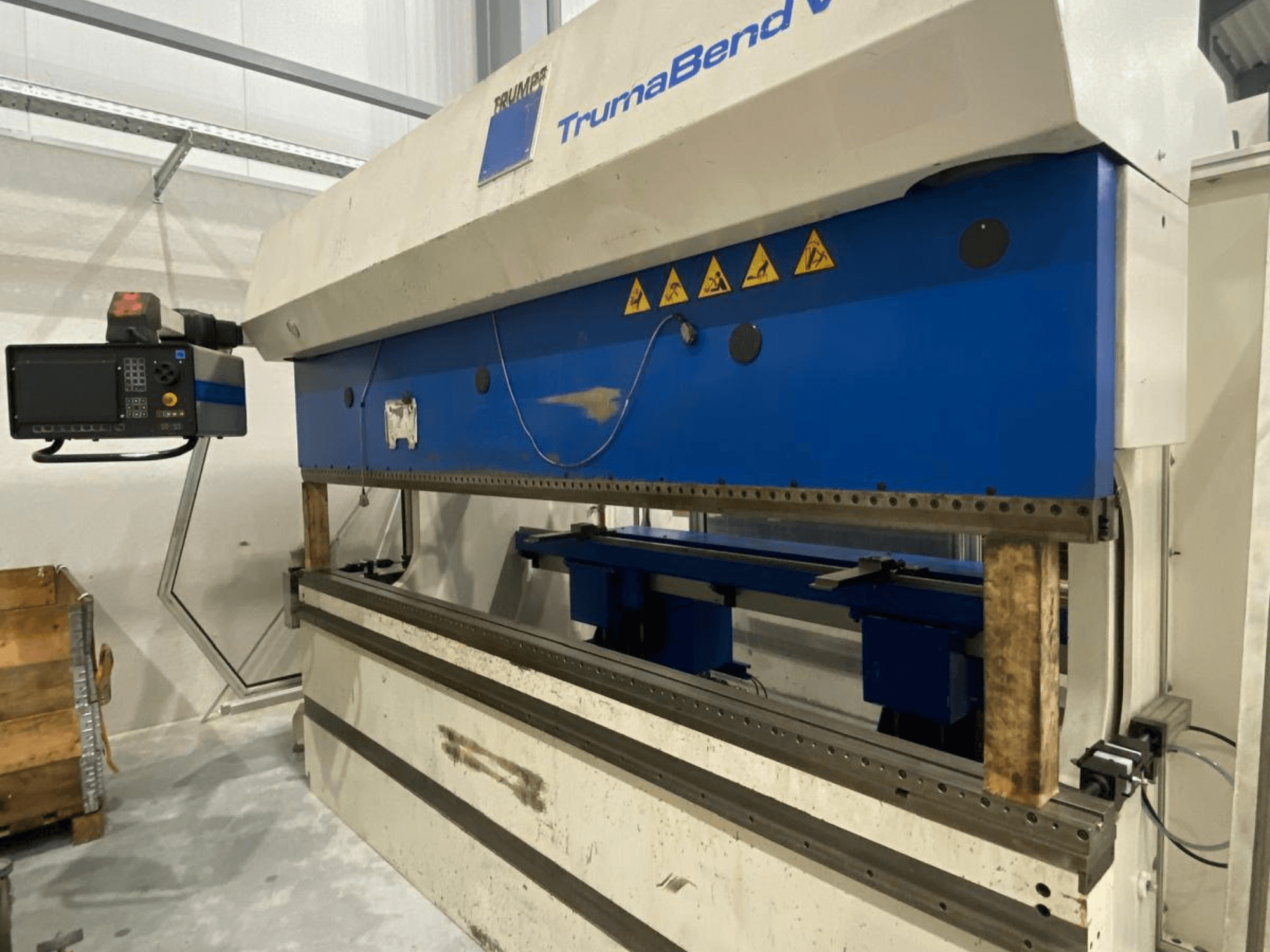 Piegatrice TRUMPF Trumabend V130, vista frontale, con pannello di controllo, elementi blu ed etichette di avvertenza di sicurezza visibili.