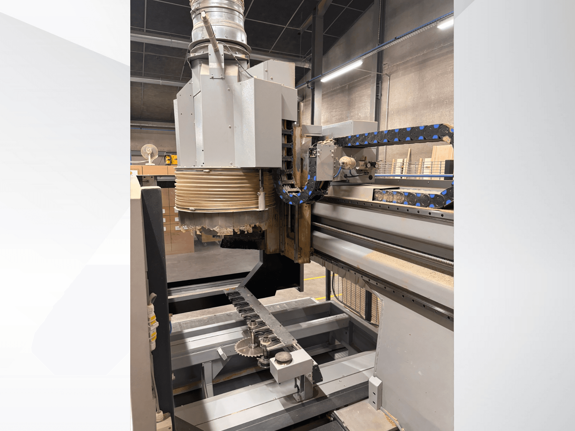 Macchina per fresatura a controllo numerico con un grande mandrino e un convogliatore, vista laterale, che mostra gli utensili per il taglio del legno e i componenti della macchina.