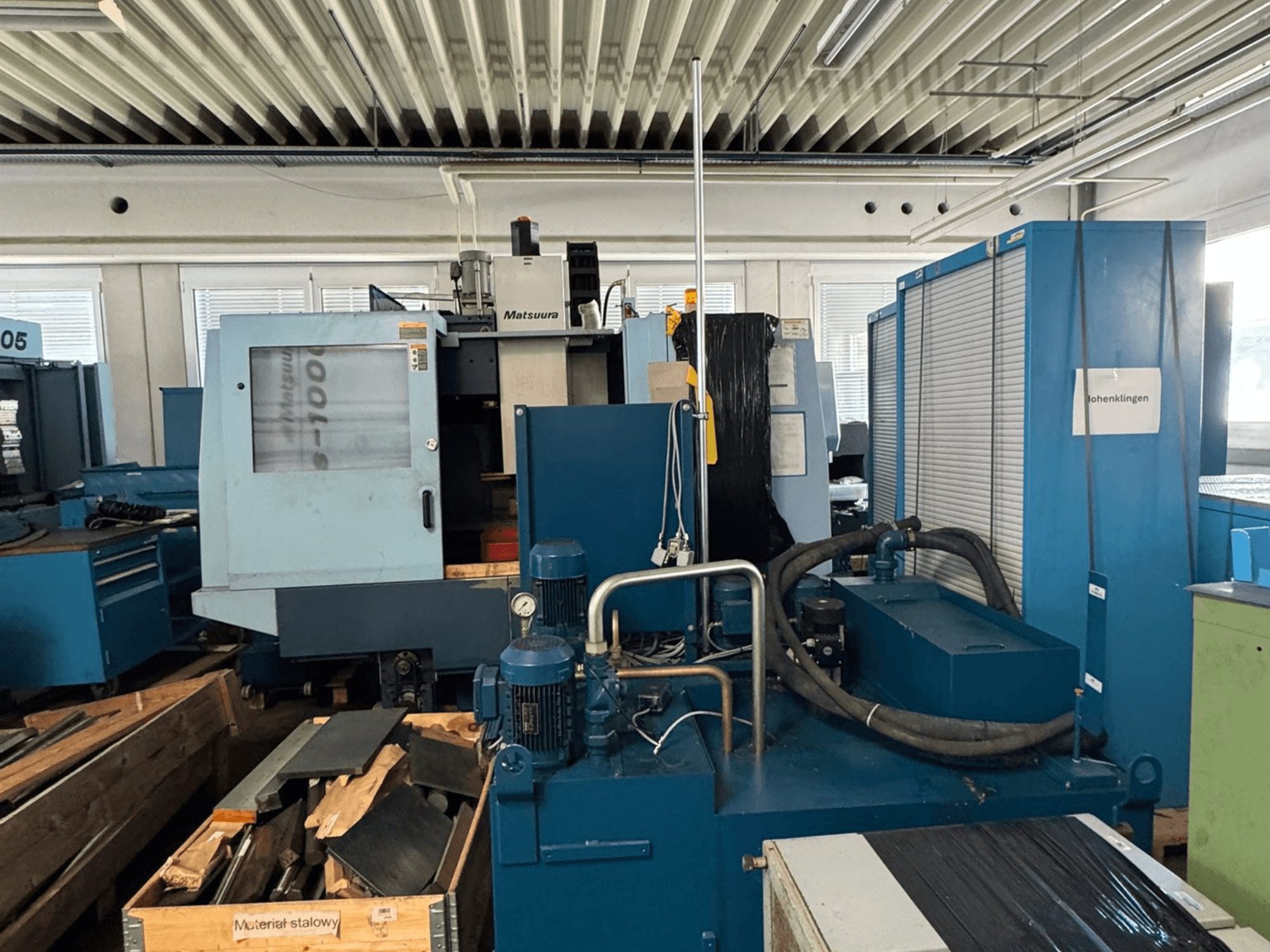 Vista frontale del centro di lavorazione verticale Matsuura Vplus 1000/40, con i comandi, i motori e l'ambiente circostante dell'officina.