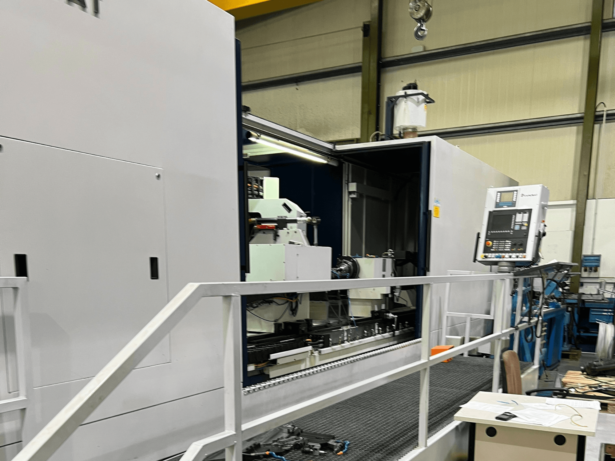 Centro di lavoro CNC con vista laterale aperta, che mostra i comandi, il portautensili e il componente principale all'interno. I dettagli del marchio non sono visibili.