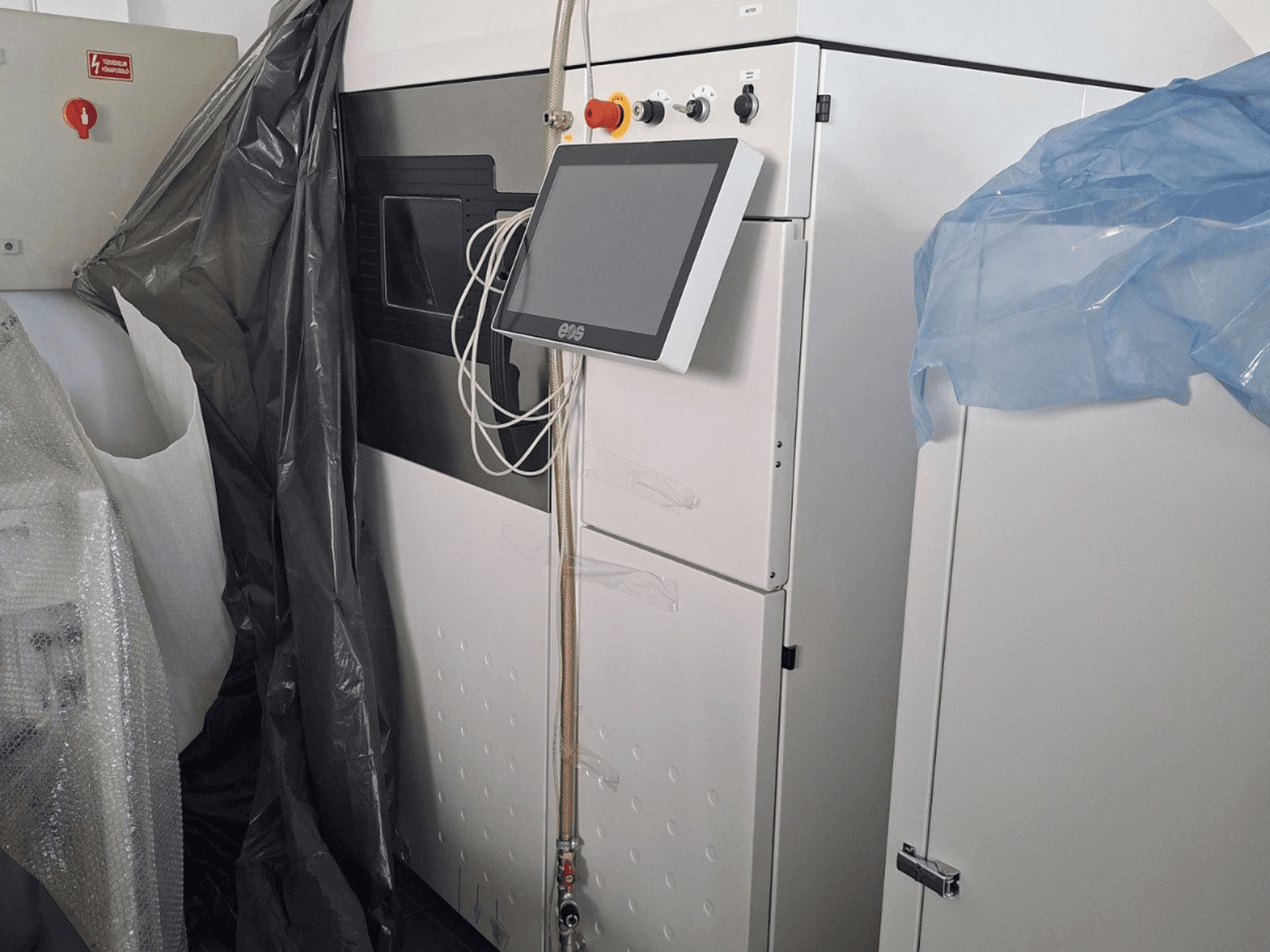 Vista frontale della stampante 3D in metallo EOS M 290, con touchscreen, pannello di controllo e coperture protettive.