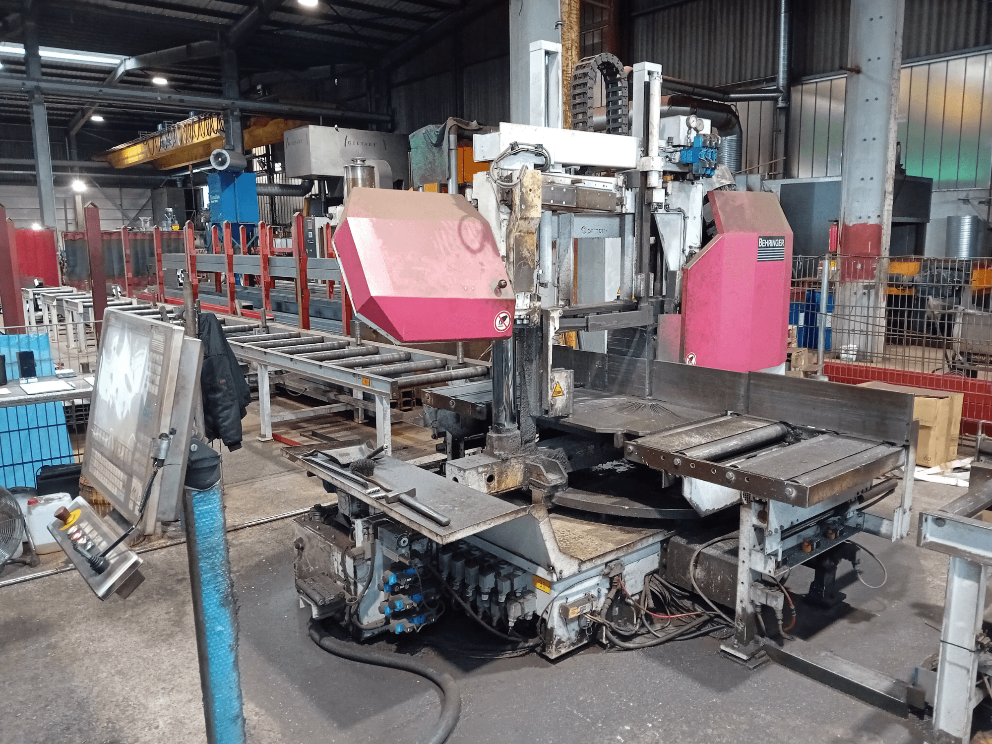 Segatrice a nastro Behringer in una fabbrica, vista frontale, con una grande lama di taglio e un pannello di controllo con pulsanti.