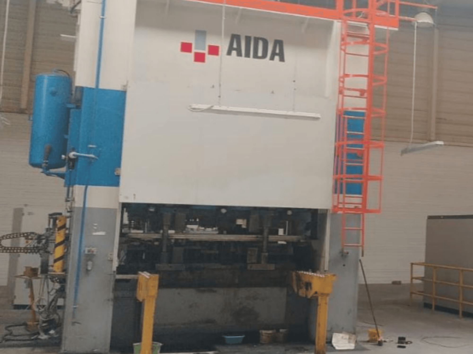 Pressa di tranciatura meccanica AIDA 315/2MR/LD/TE3, vista frontale, con componenti idraulici e scala di sicurezza.