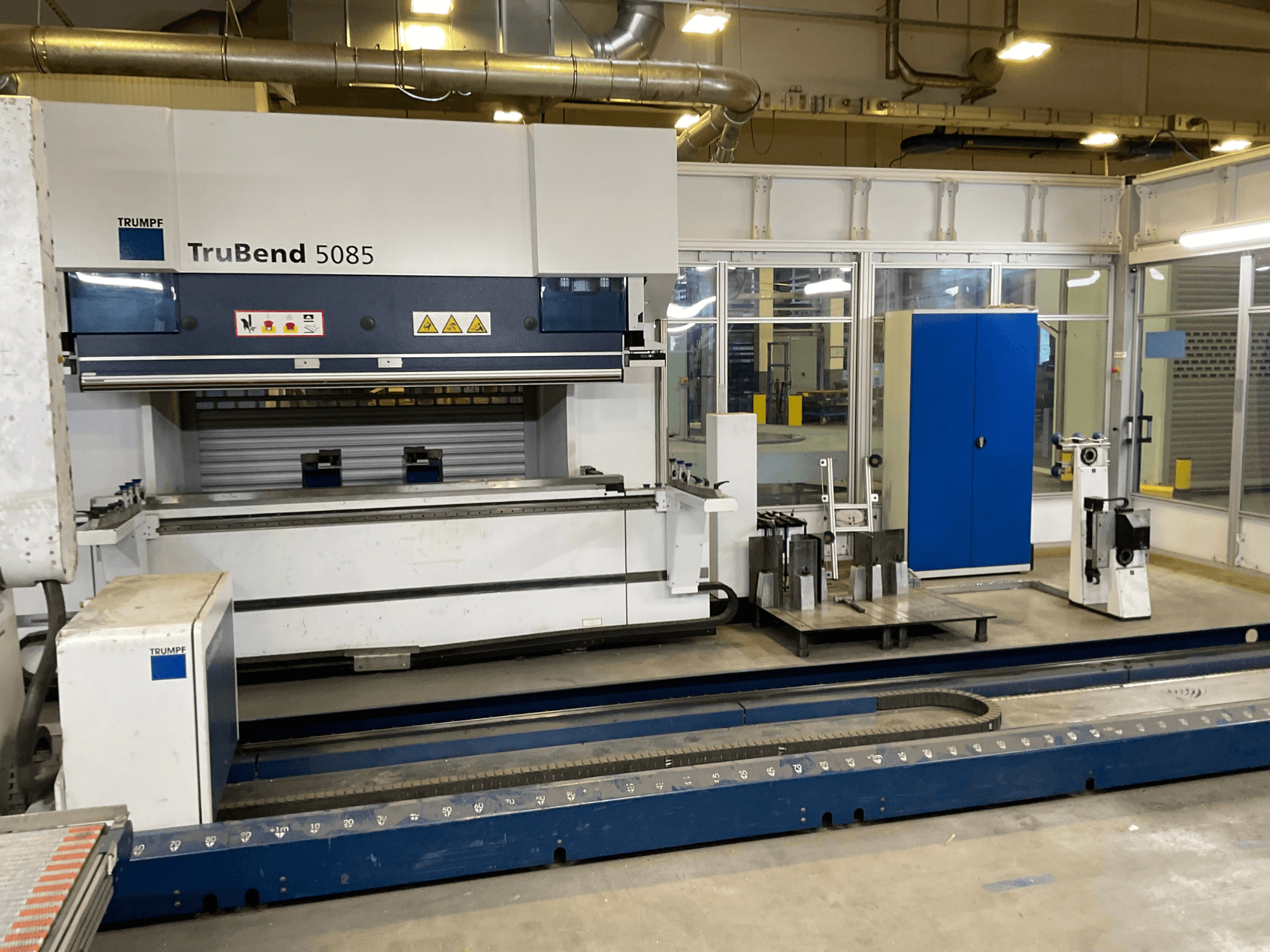 TruBend 5085 di TRUMPF, vista laterale di una grande piegatrice di metalli con pannello di controllo e vari strumenti accanto.